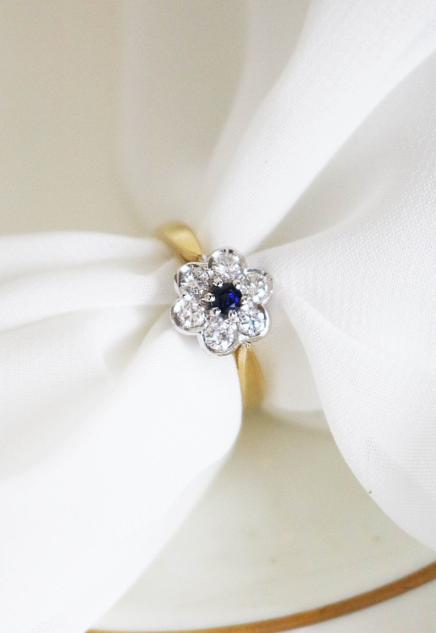 Florah 18ct white gold center piece with diamond and sapphire flower on a 18ct yellow gold band. A white napkin is threaded through the band.  Canadian vintage engagement rings. Bridal jewelry Canada. Canadian weddings. Wedding Canada. Canadian bridal jewelry. Woman-owned Canadian jewelry brand. Canadian jewelry brands.