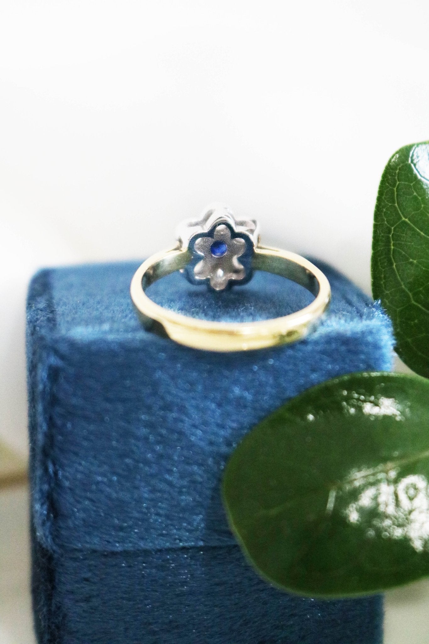 A close up back view of the Florah Diamond Flower and Sapphire Vintage Engagement Ring on top of a dark blue ring box. Canadian vintage engagement rings. Bridal jewelry Canada. Canadian weddings. Wedding Canada. Canadian bridal jewelry. Woman-owned Canadian jewelry brand. Canadian jewelry brands.