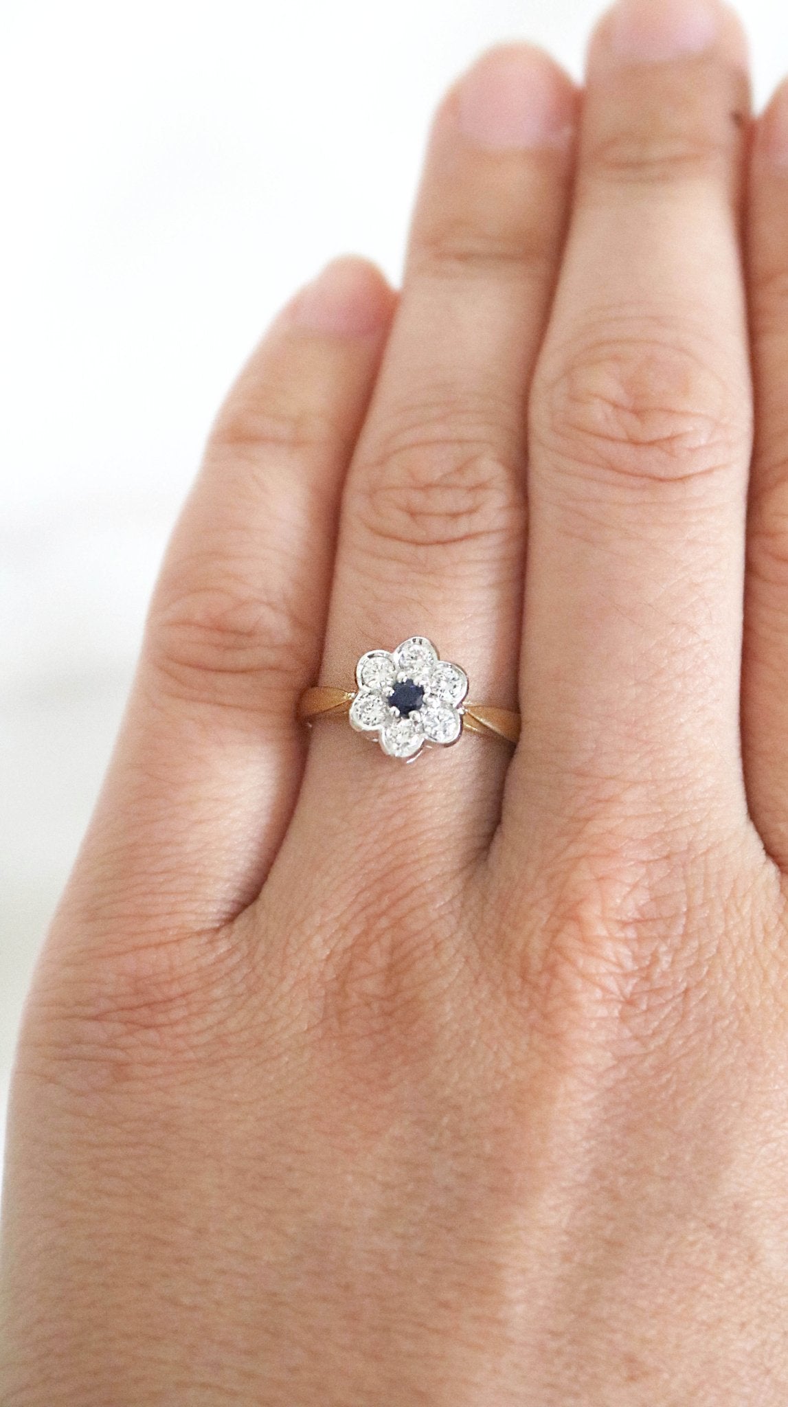 The Florah Diamond Flower and Sapphire in 18ct white and yellow gold Vintage Engagement Ring on a ring finger. Canadian vintage engagement rings. Bridal jewelry Canada. Canadian weddings. Wedding Canada. Canadian bridal jewelry. Woman-owned Canadian jewelry brand. Canadian jewelry brands.