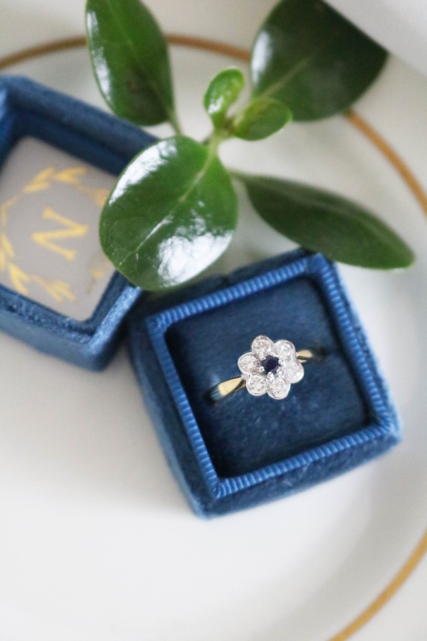 A Diamond Flower and Sapphire 18ct Gold Vintage Engagement Ring sitting in a dark blue ring box. Canadian vintage engagement rings. Bridal jewelry Canada. Canadian weddings. Wedding Canada. Canadian bridal jewelry. Woman-owned Canadian jewelry brand. Canadian jewelry brands.