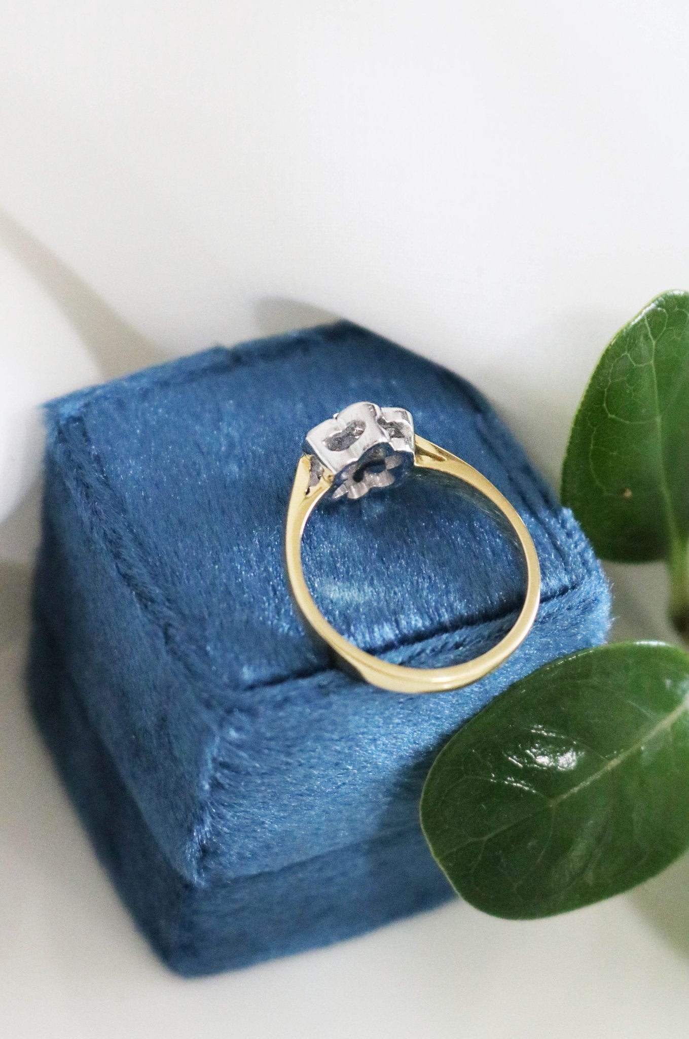 A back view of the Florah Diamond Flower and Sapphire Vintage Engagement Ring sitting on a dark blue ring box. Canadian vintage engagement rings. Bridal jewelry Canada. Canadian weddings. Wedding Canada. Canadian bridal jewelry. Woman-owned Canadian jewelry brand. Canadian jewelry brands.