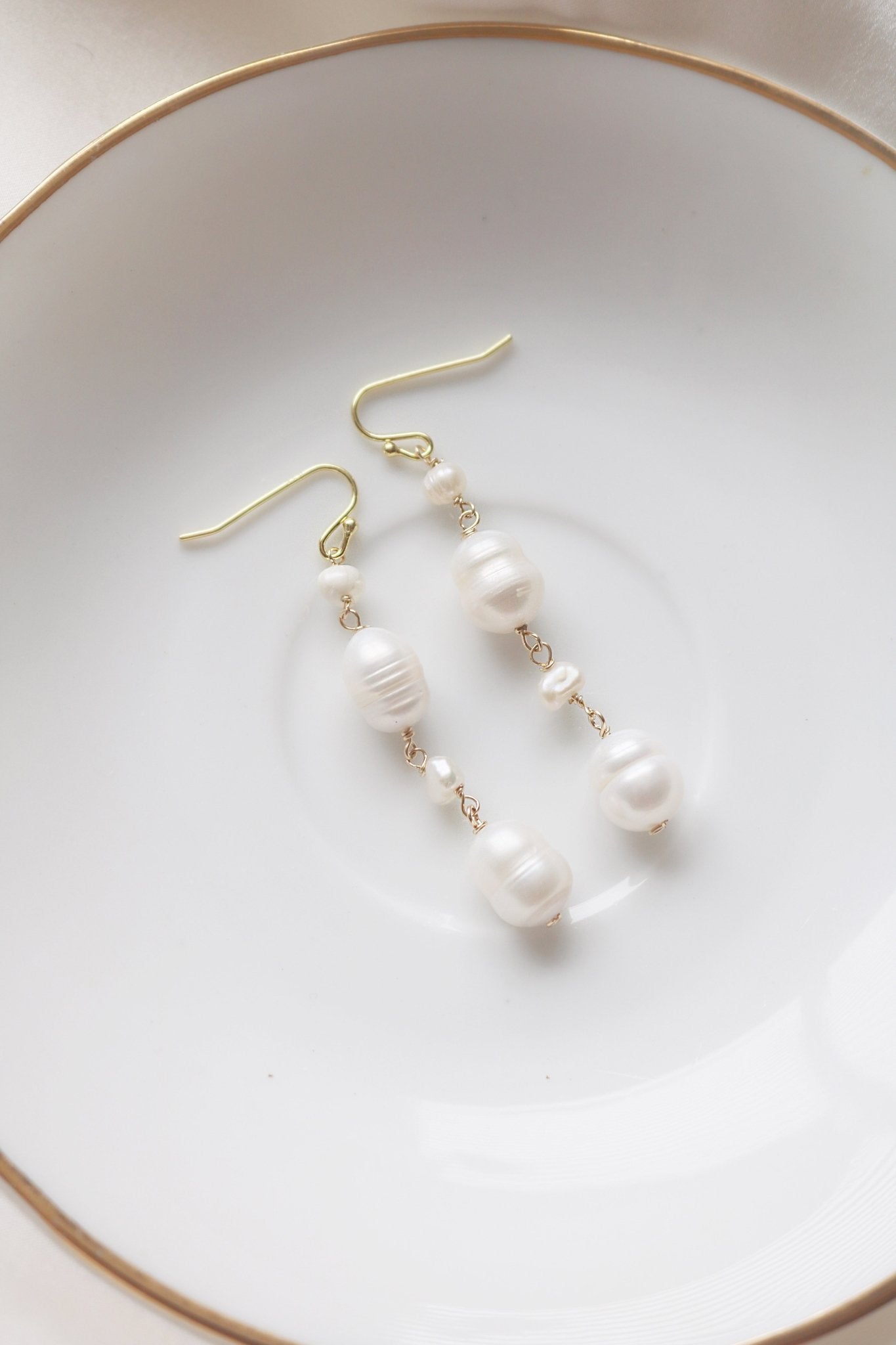 Gold-filled Frida Fresh Water Pearl Drop Earrings on a Ceramic Plate for Display.