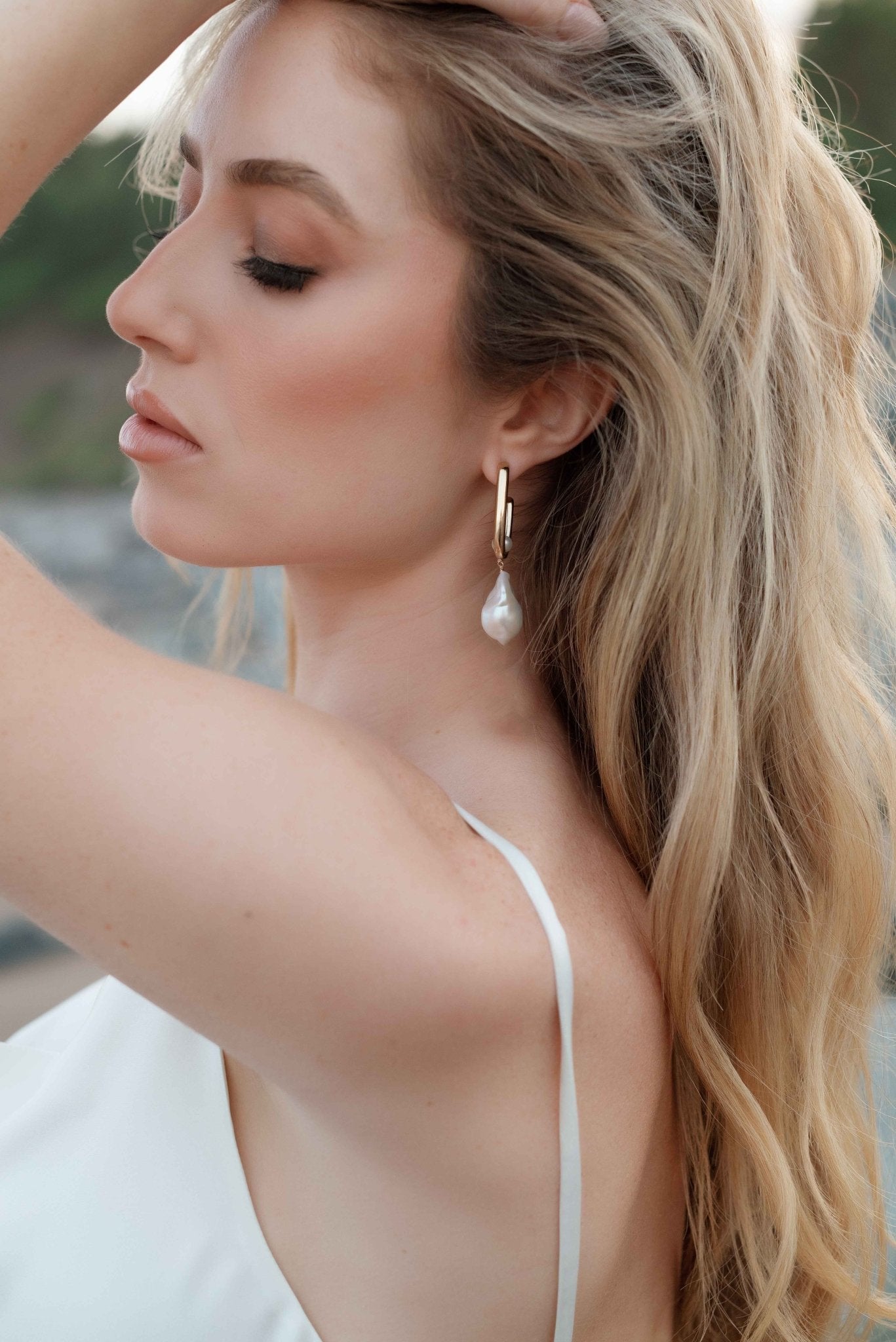 Whimsical bride poses to show off her gold-filled-baroque-freshwater-pearl bridal earrings. 