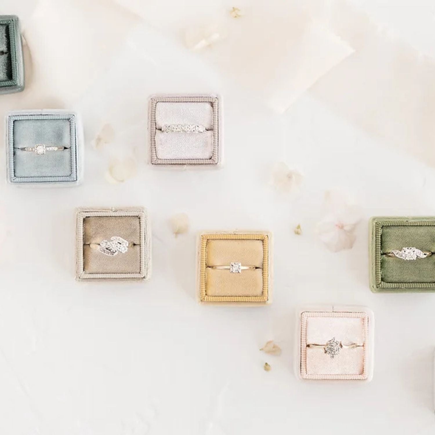 Multiple gold and diamond vintage engagement rings in multi-coloured velvet ring boxes on neutral background. Antique engagement rings & vintage rings Canada