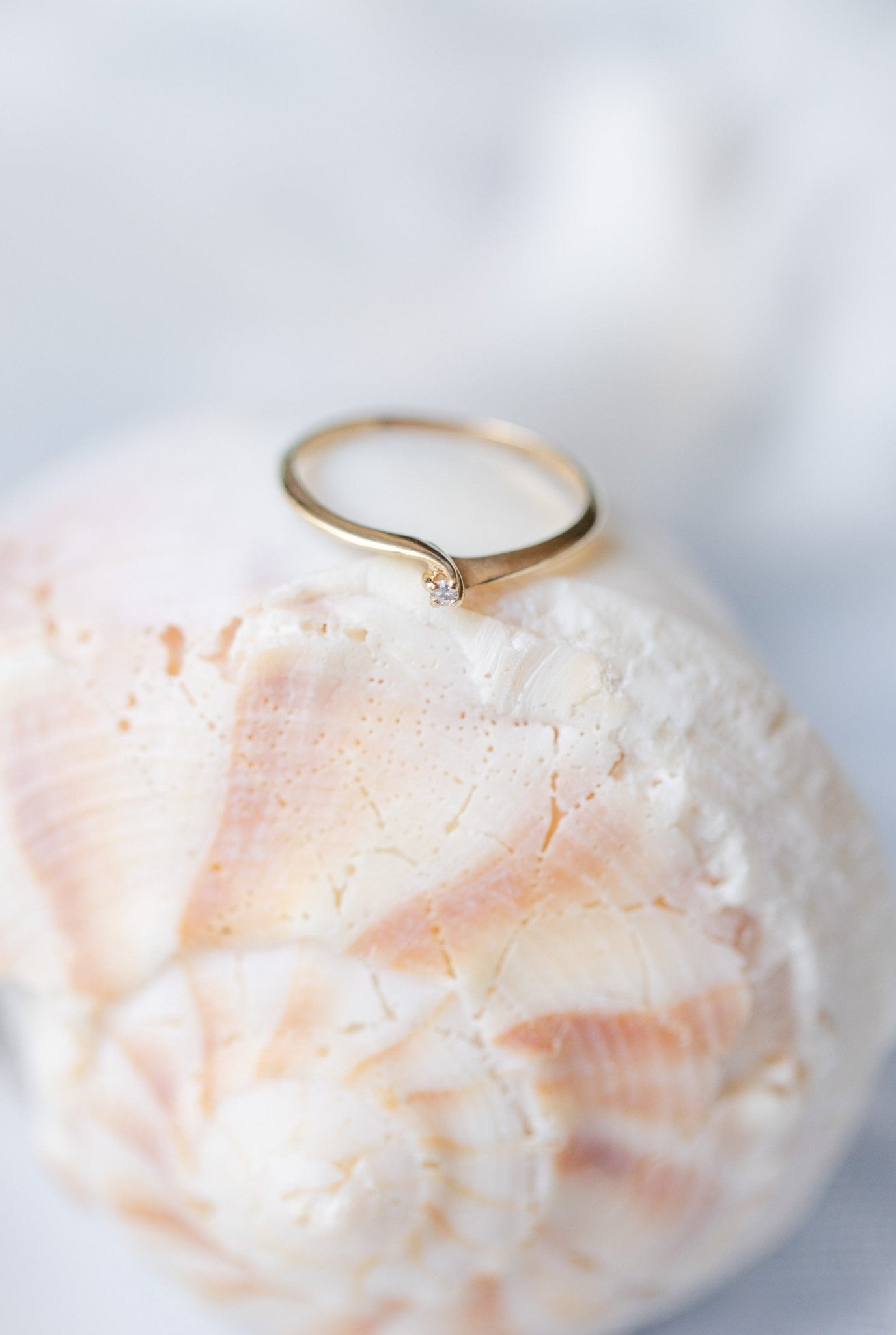 A Hale 14K Yellow Gold Vintage Diamond Engagement Ring sits on top of a large seashell. 