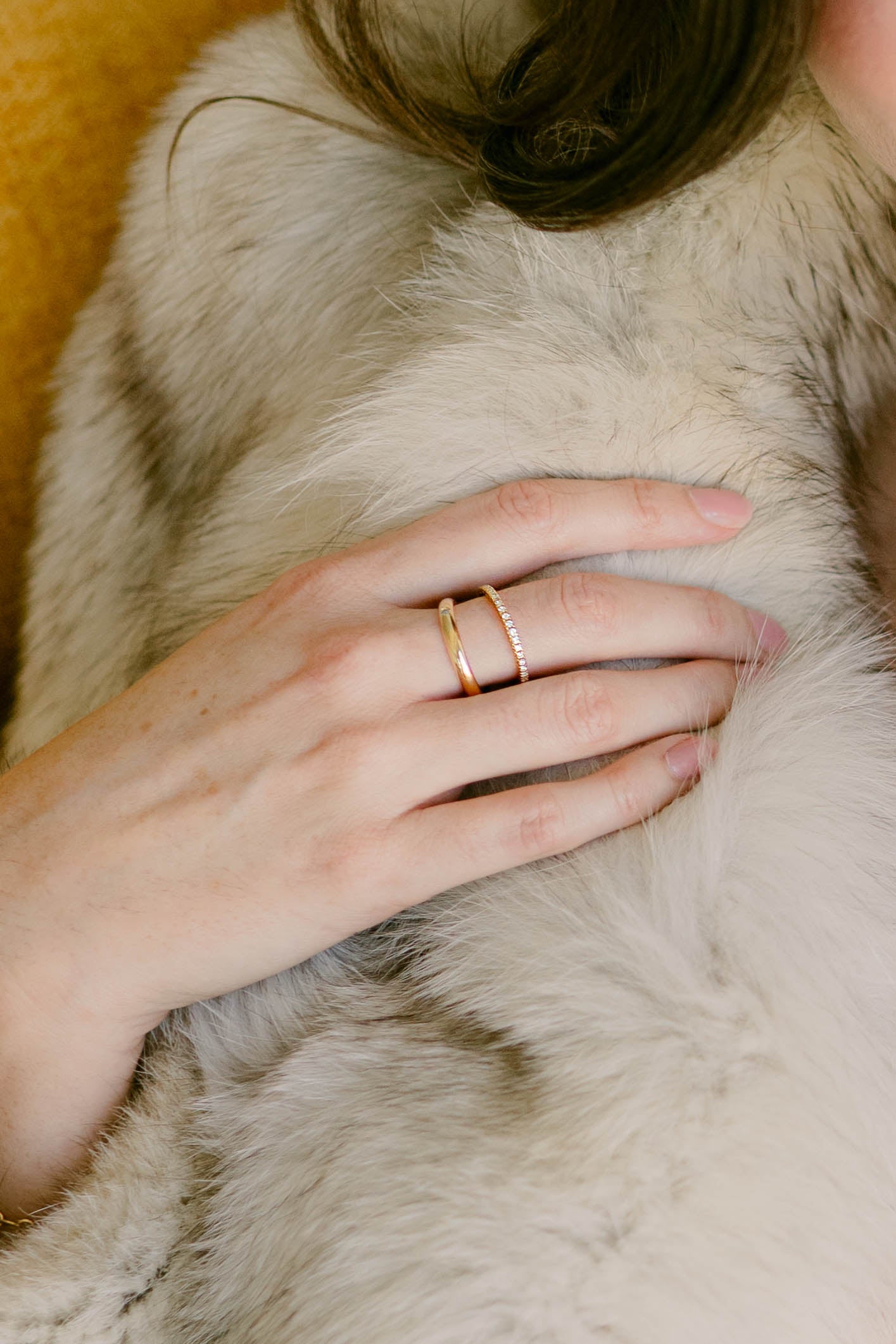 Hand resting on fur coat wearing 2 gold-filled rings with tiny cubic zirconia crystals. Gold-filled Canadian jewelry. Canadian artist.