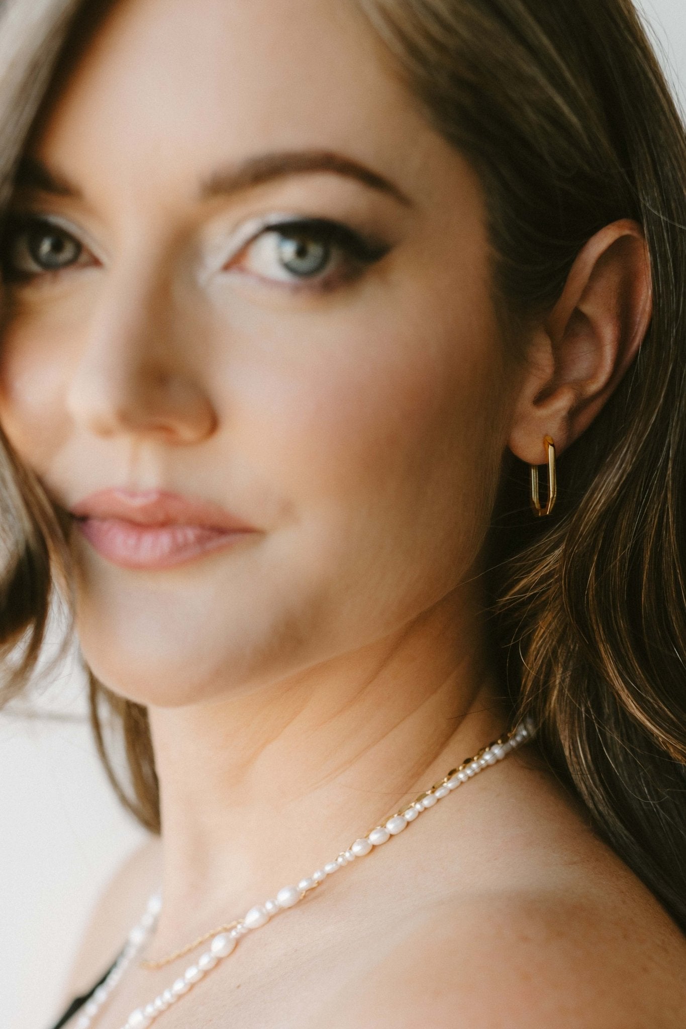 Close-up of a woman wearing a pearl necklace and hoop earring. Modern jewelry. Minimalist jewelry. Canadian handmade jewelry.