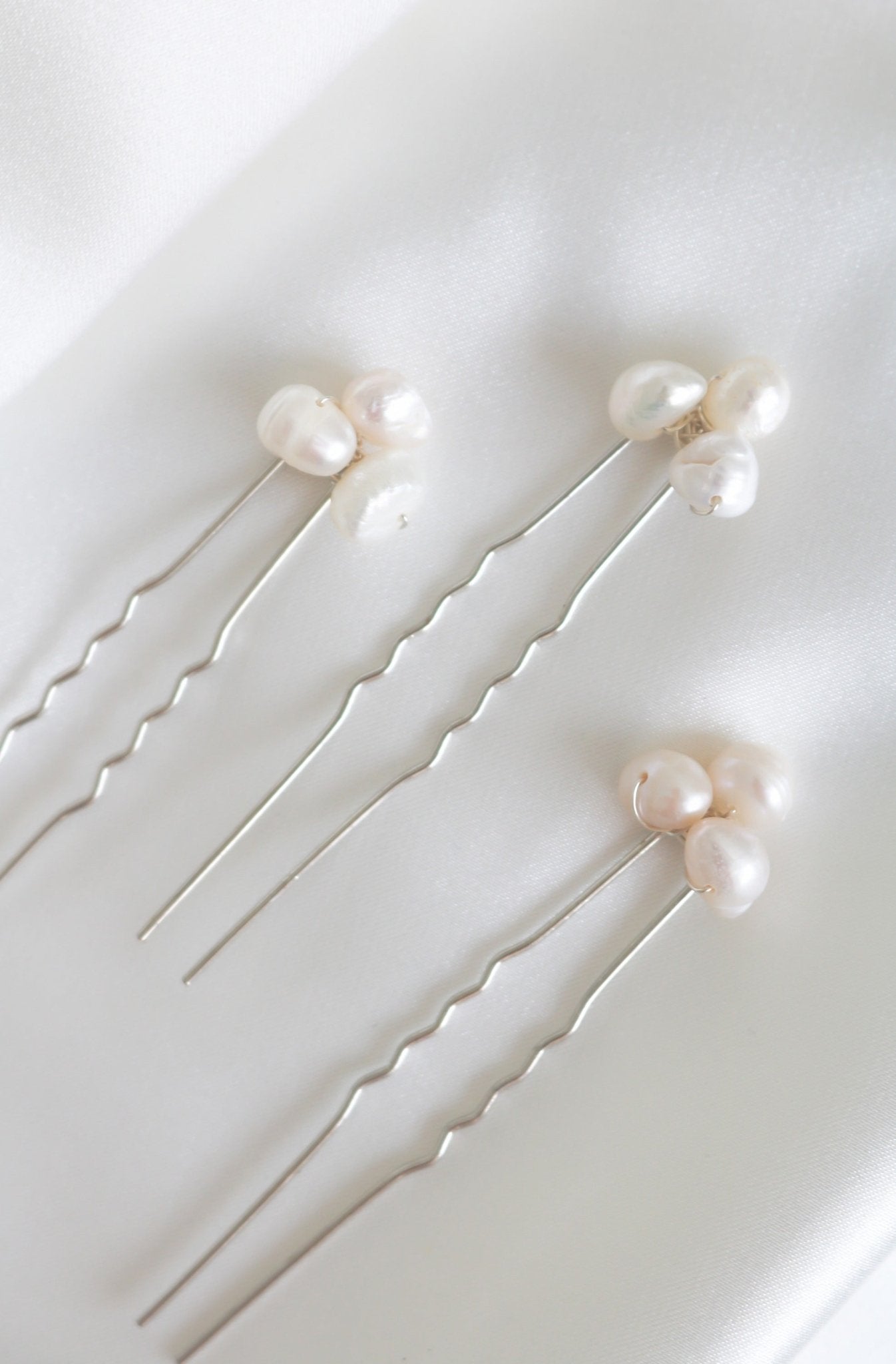 Three silver bridal hairpins with organic freshwater pearls on white background.