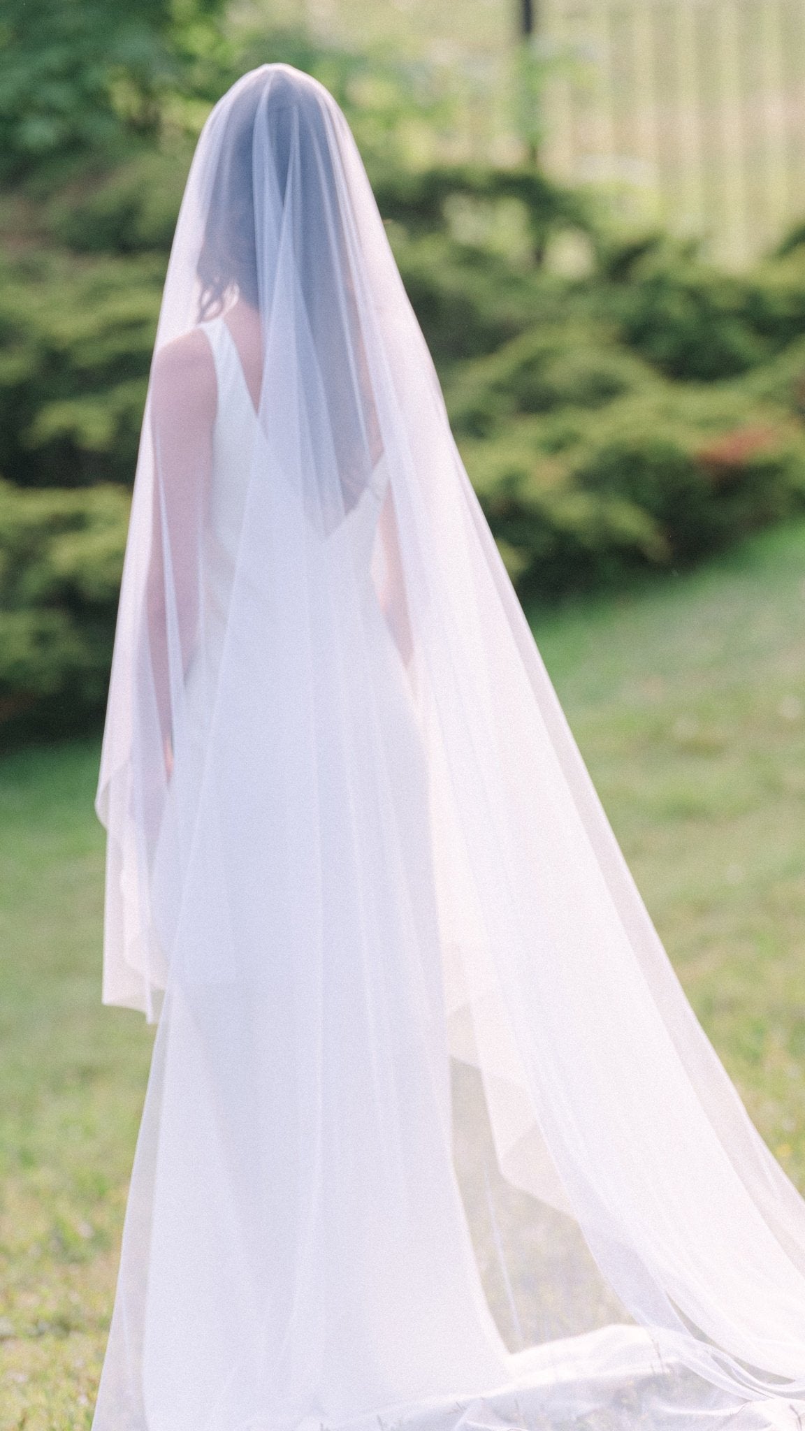 A gorgeous flowing full heavenly bridal veil with blusher falls to the ground behind a bride.