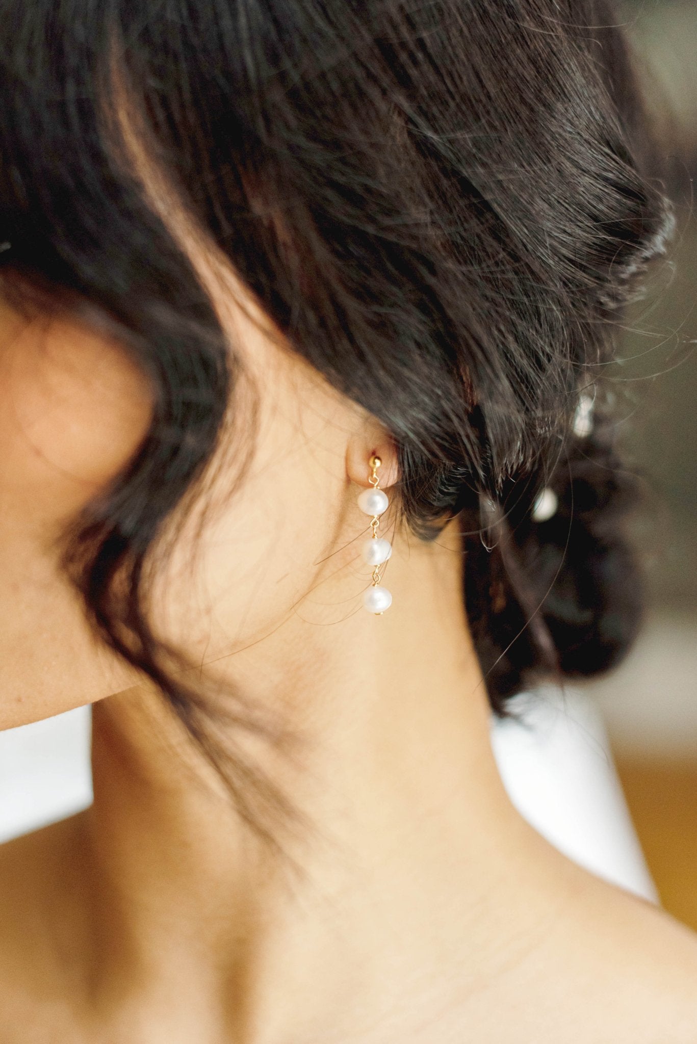 Gold-filled Isla Drop Fresh Water Pearl Studs Dangle from a Bride's Ear.