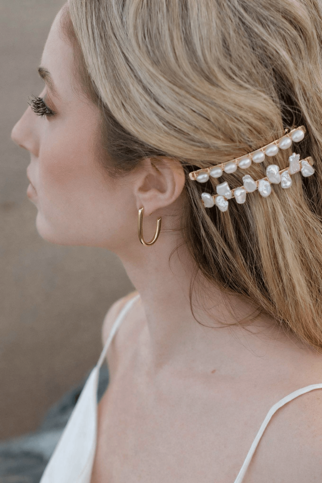 Woman wearing a gold hair accessory with freshwater pearls and gold-filled J-shaped earrings. Modern jewelry & everyday jewelry handmade by Canadian BIPOC jewelry designer
