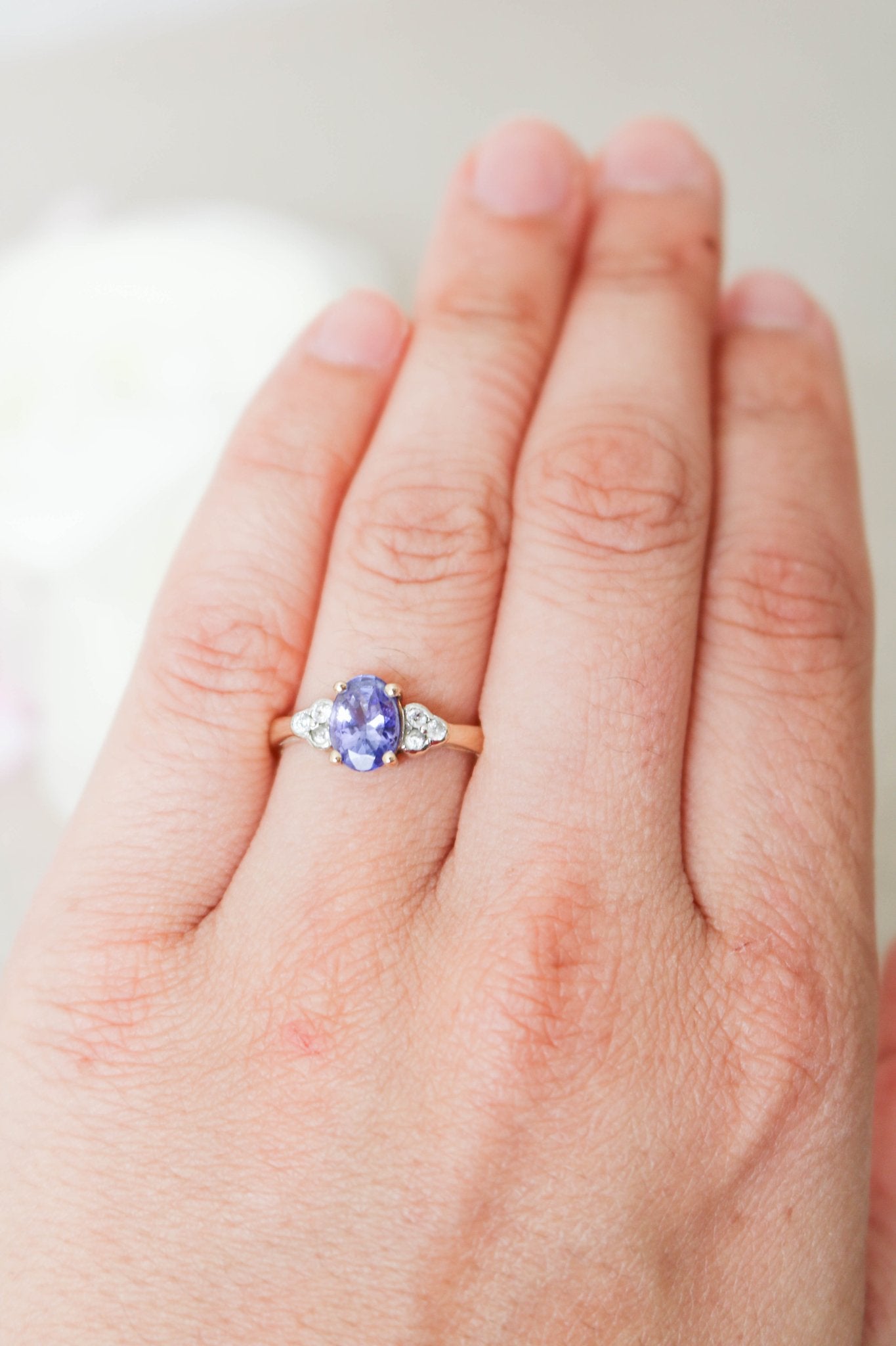 The Jolie Violet Tanzanite and White Topaz 9ct Vintage Engagement Ring on a ring finger. 