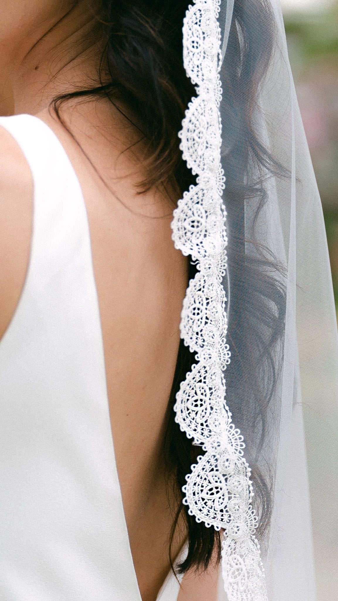 Close up view of lace detailing on white scallop-edged bridal wedding veil. 