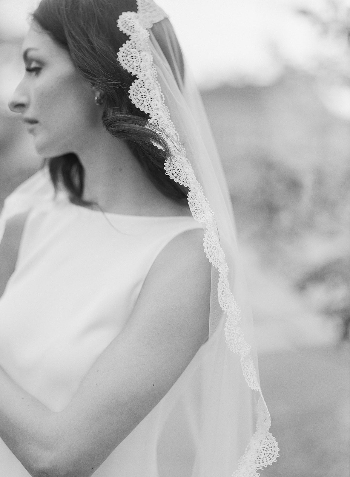 Black and White photo of a bride on her wedding day wearing a delicate detailed lace bridal veil. 