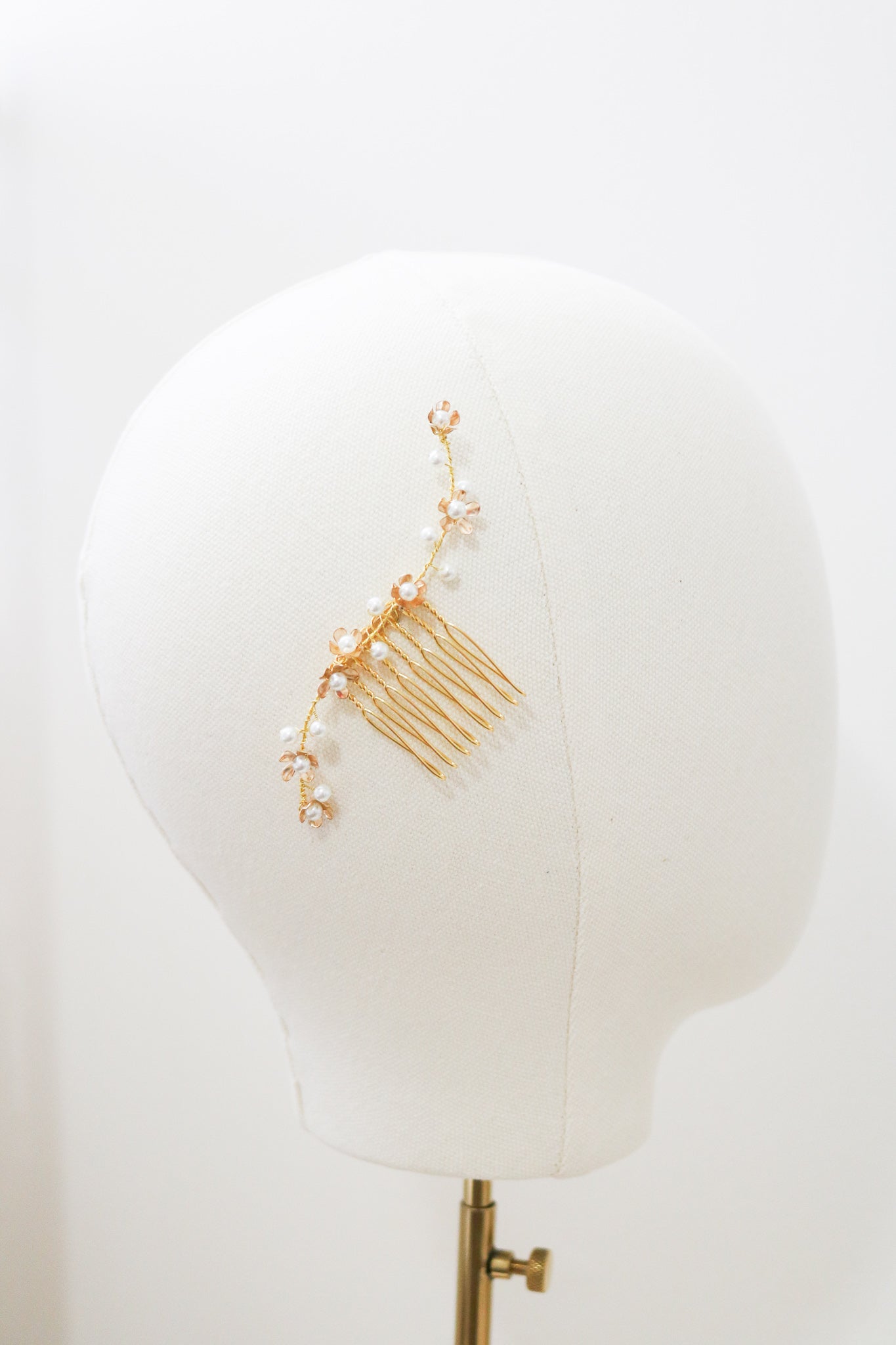 A shorter gold freshwater pearl floral bridal hair comb displayed on the side of a mannequin head.