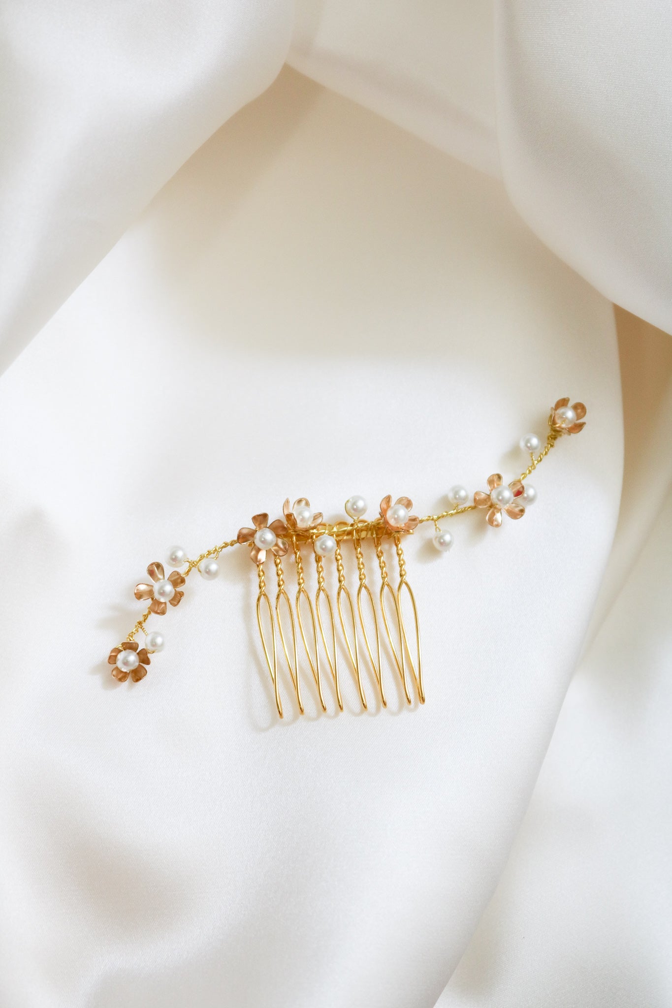 A close up of a shorter gold freshwater pearl floral bridal hair comb displayed on the side of a mannequin head.