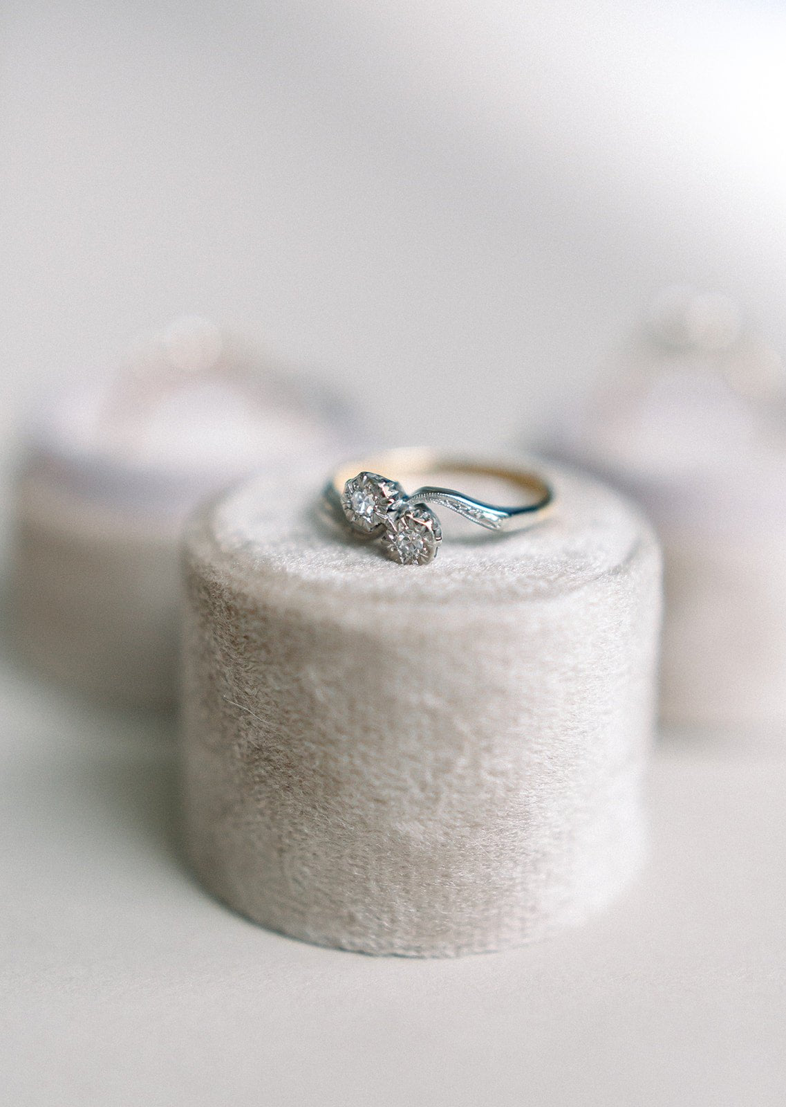 A Lacey Diamond Vintage Engagement Ring in 18k Yellow Gold and Platinum c.1920's sits on top of a textured display stand.