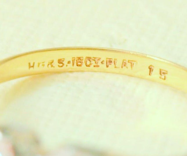 An extreme close up of the inside of the Lacey 18k gold diamond ring's stamped information. 