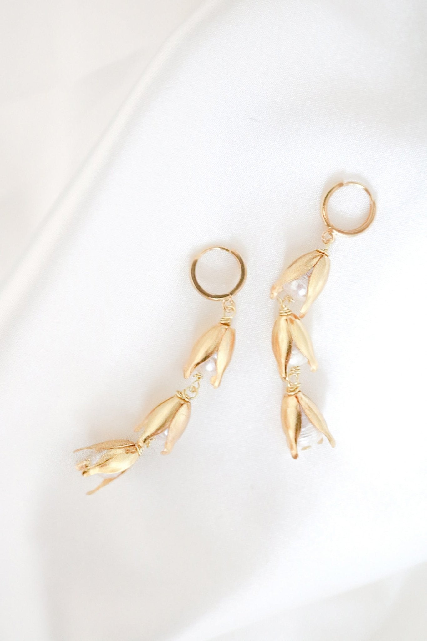 A pair of dangly gold-filled freshwater pearl huggie earrings. 