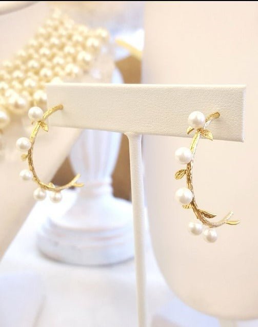 A pair of Gold-Filled Laurel Freshwater Pearl & Branch Hoops hanging on a display. Bridal jewelry Canada. Pearl jewelry Canada. Pearl Bridal jewelry Canada. Gold-filled jewelry Canada. Gold-filled Canadian jewelry. Handmade Canadian jewelry. Canadian handmade jewelry. Small Canadian jewelry brands. Canadian jewelry brands.