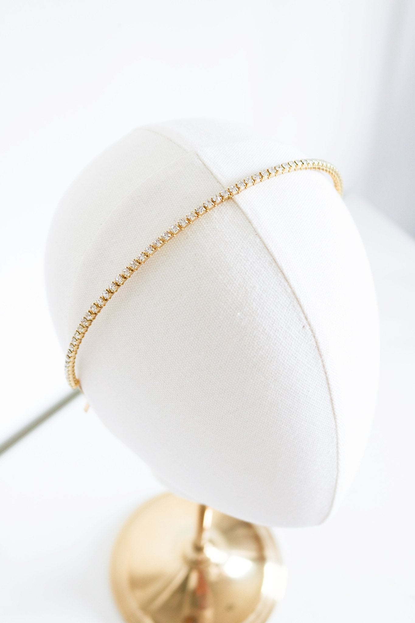 A Gold Crystal bridal headband displayed on a white head bust against white background. Bridal hair accessories & Canadian hair accessories handmade by Canadian BIPOC jewelry designer
