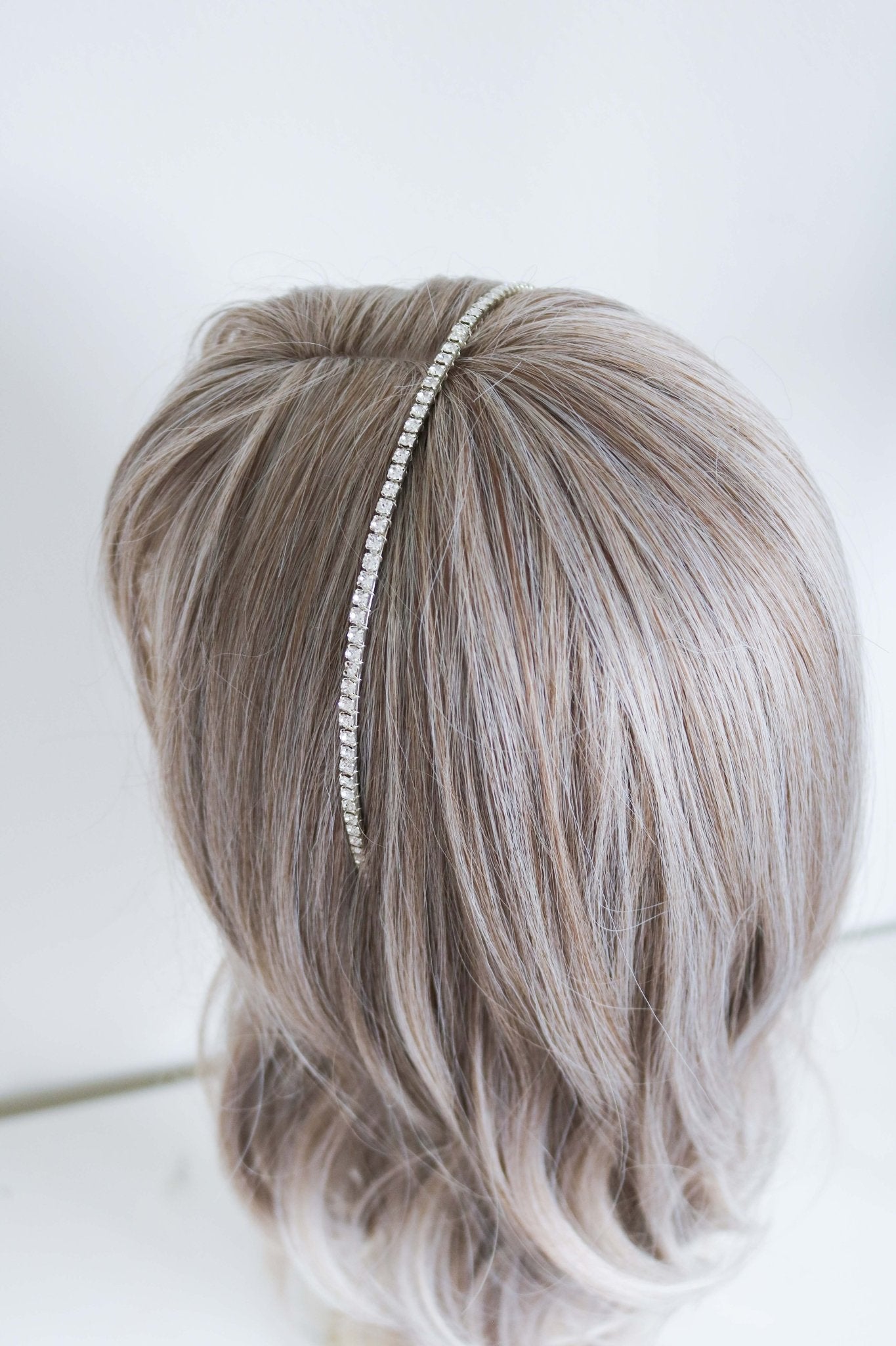 A Silver Crystal Halo Headband in a head bust's hair.