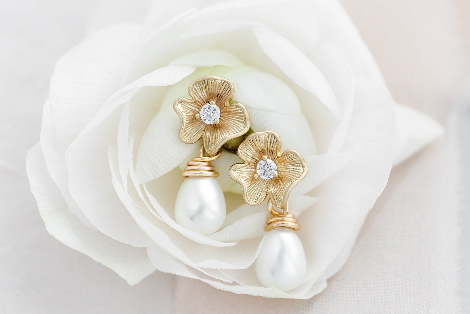 A pair of gold-filled flower earrings with freshwater pearl drops and crystal centers on a white rose. Bridal jewelry Canada. Pearl jewelry Canada. Pearl Bridal jewelry Canada. Gold-filled jewelry Canada. Organic pearl jewelry. Handmade Canadian jewelry.