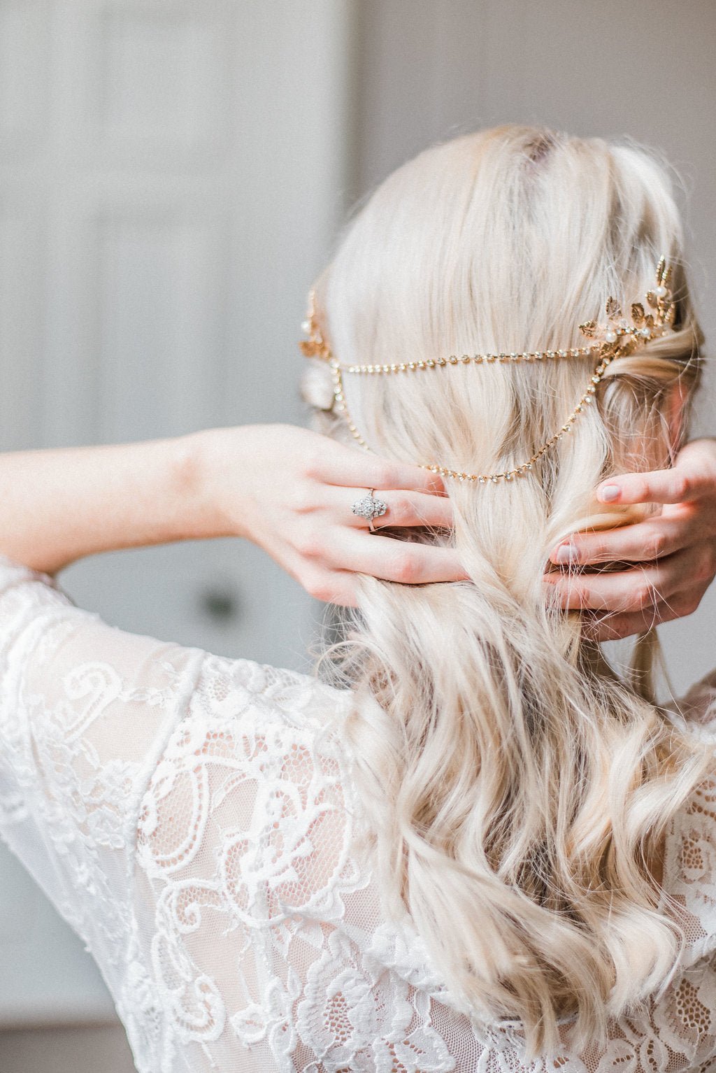 A bride showcases her golden hairpiece with draping crystals and freshwater pearl leaves across the back of her hair.