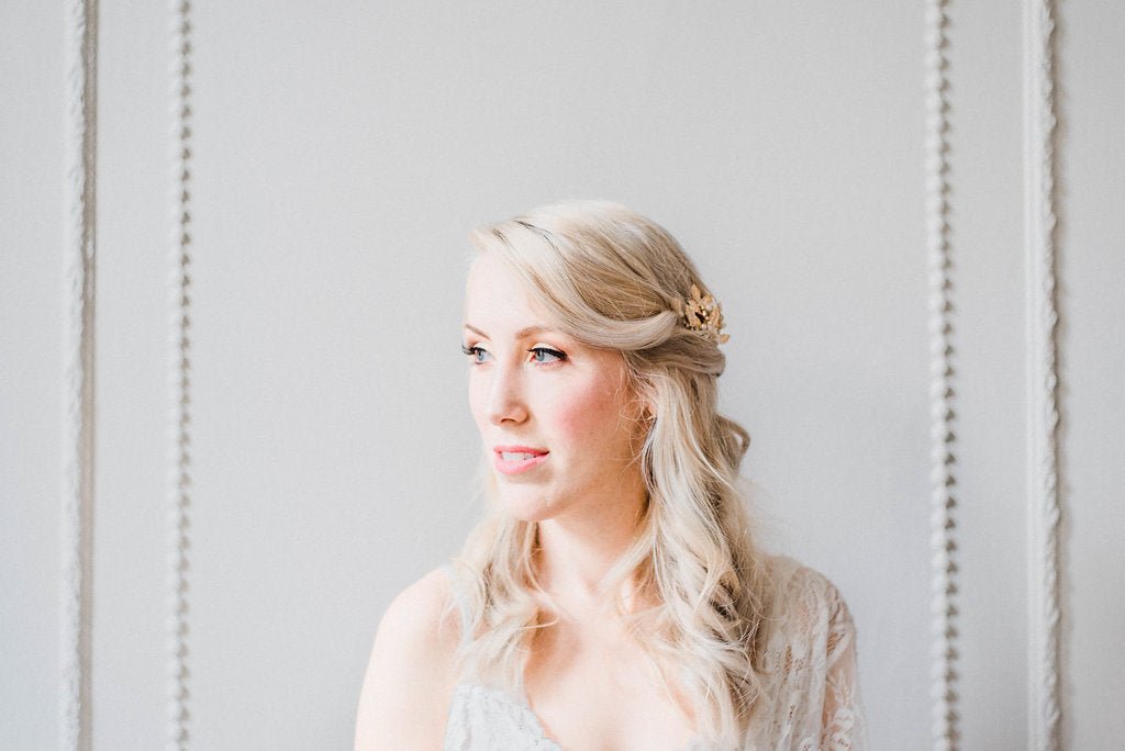 Front view of a bride looking off to the side; her golden crystal hairpiece glistening against the side of her blonde hair.