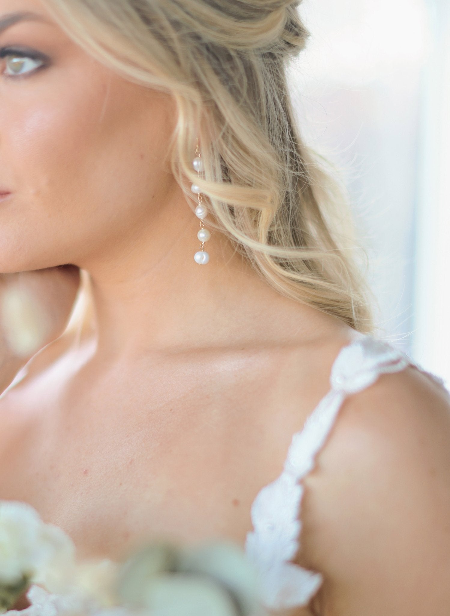 Long Statement Fresh Water Pearl Bridal Earrings hang from a bride's ear. 