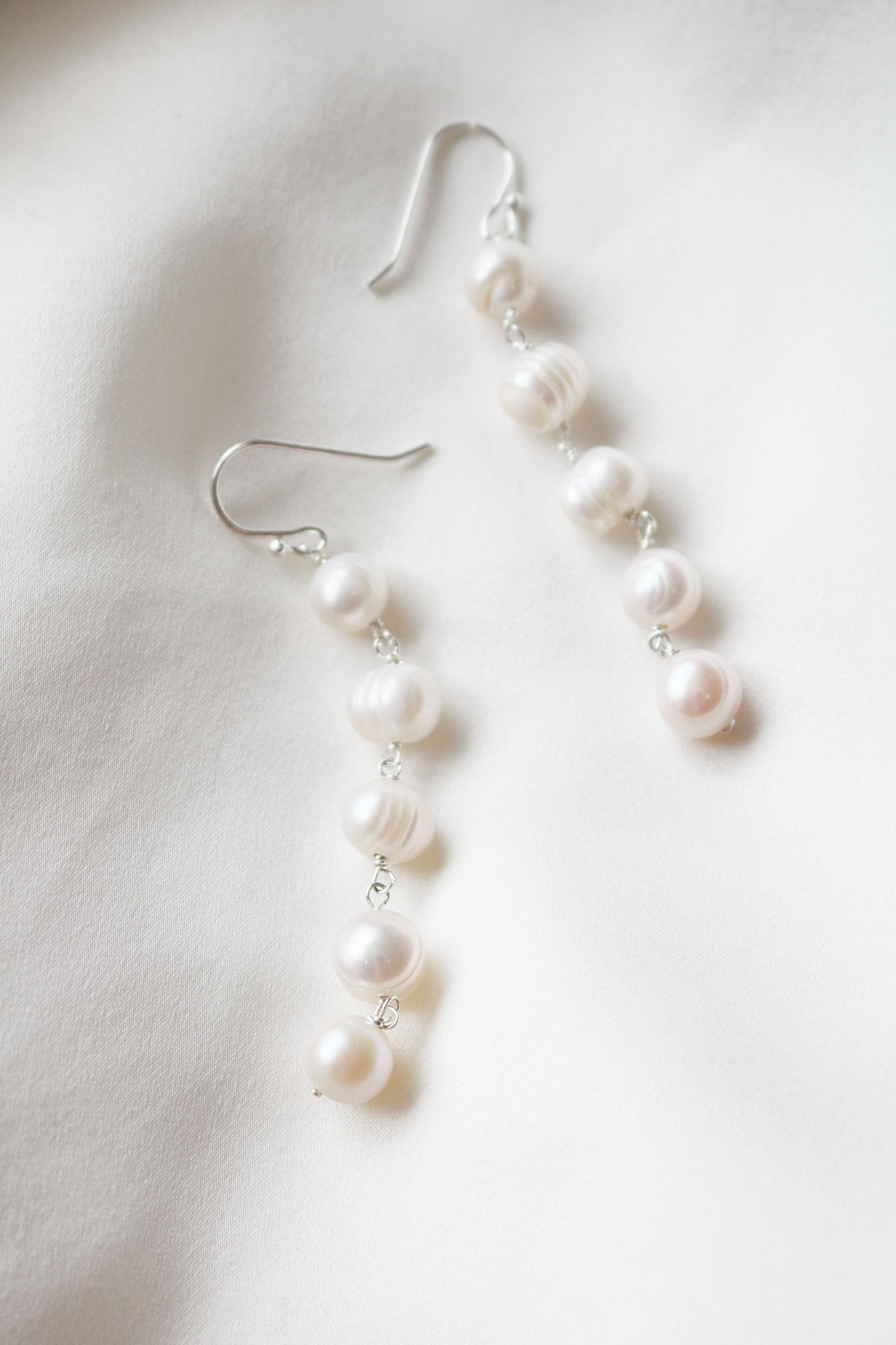 Maisie Long Statement Fresh Water Pearl Earrings in Silver on a white background. 