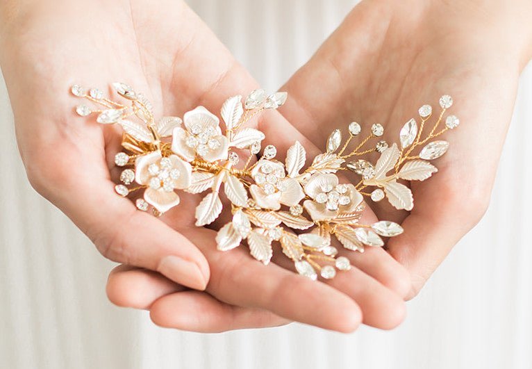 Rose gold floral hairpiece with Swarovski crystals held delicately between two hands against a white bridal gown. Canadian bridal accessories, Bridal hair accessories, & handmade wedding accessories Canada