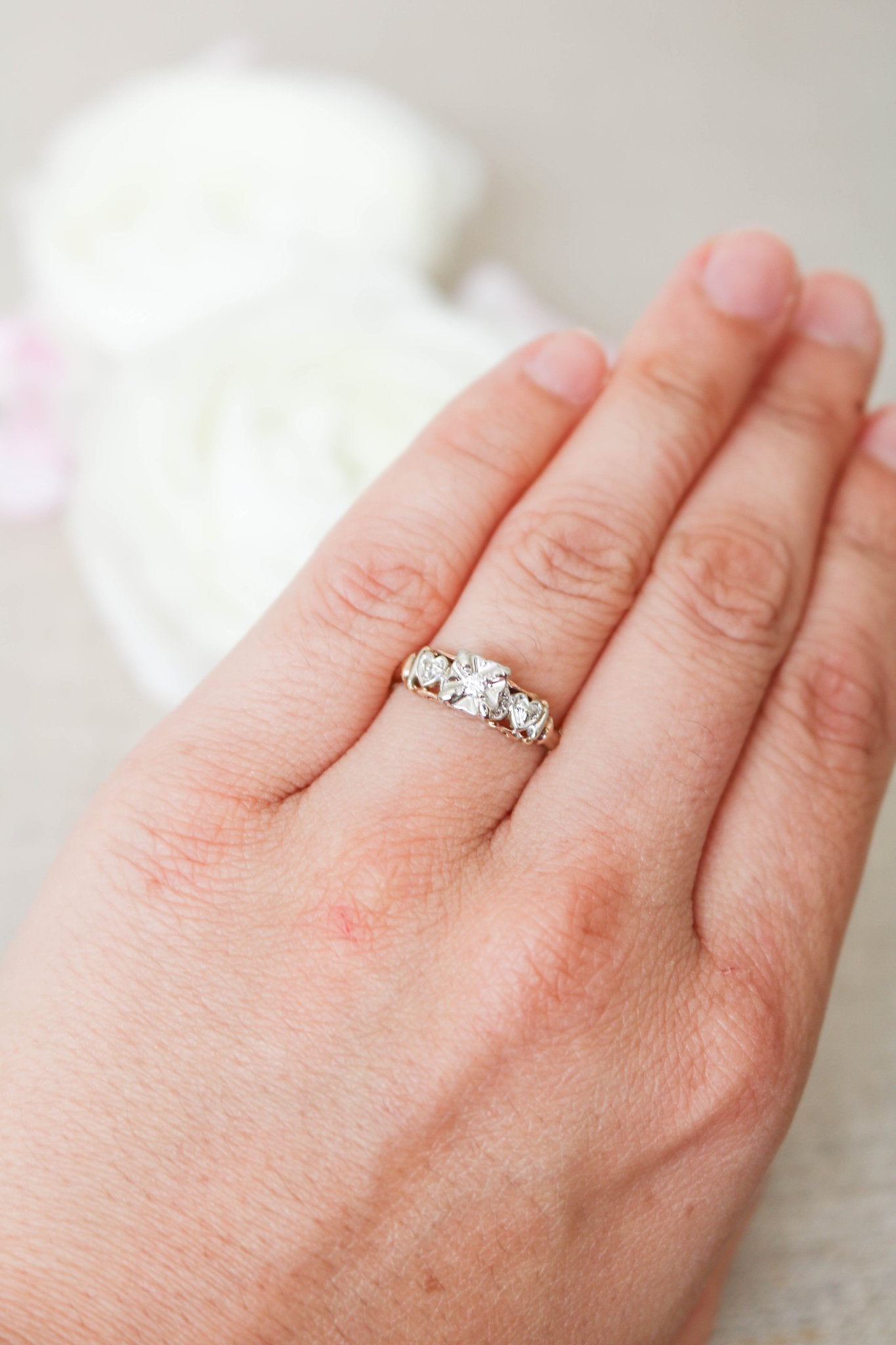 A 14ct Yellow and White Gold Vintage Engagement Ring with Diamond hearts on a ring finger. 