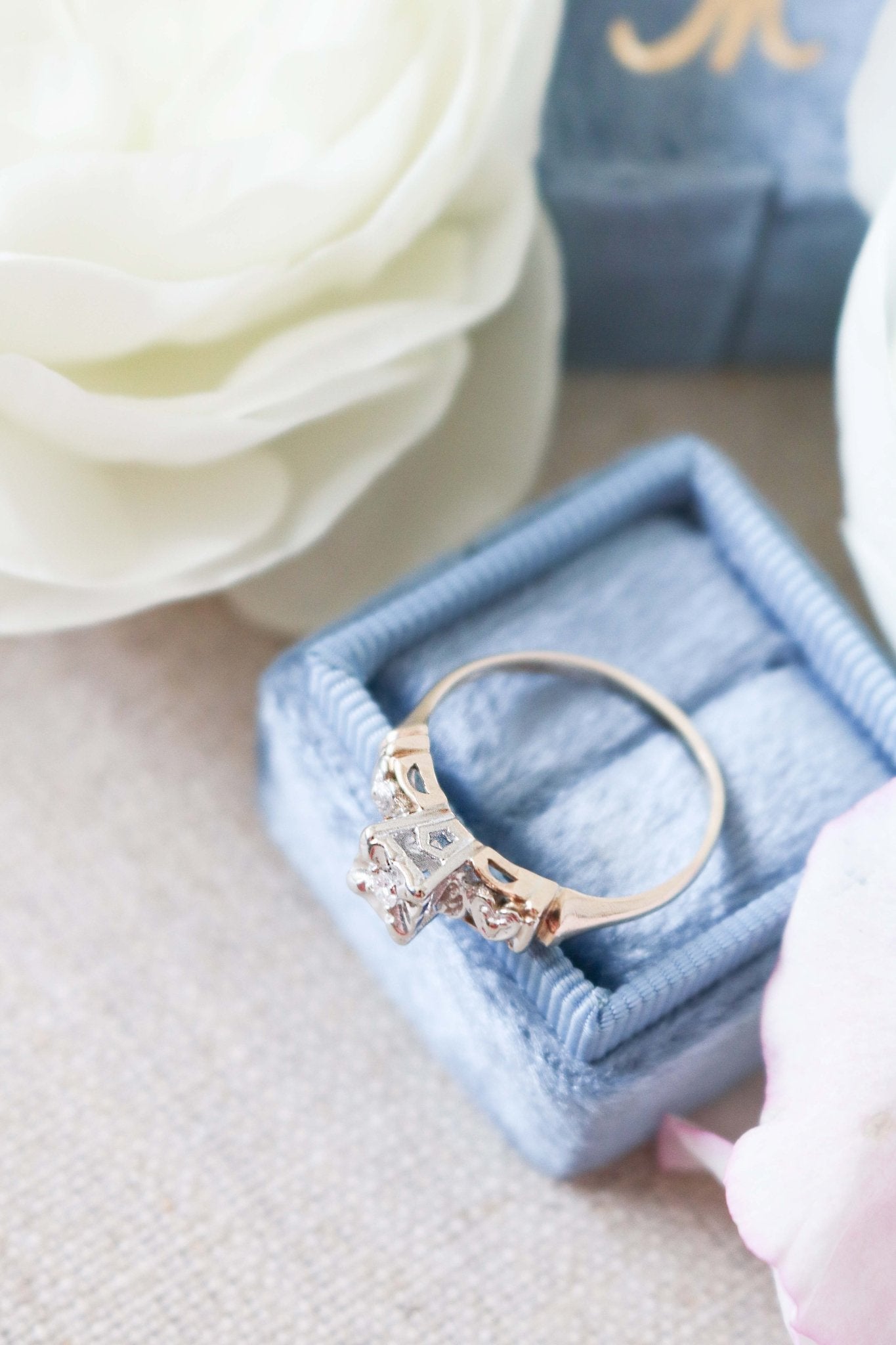 Top view of Yellow and White Gold Vintage Engagement Ring with Diamond Hearts on top of ring box. 