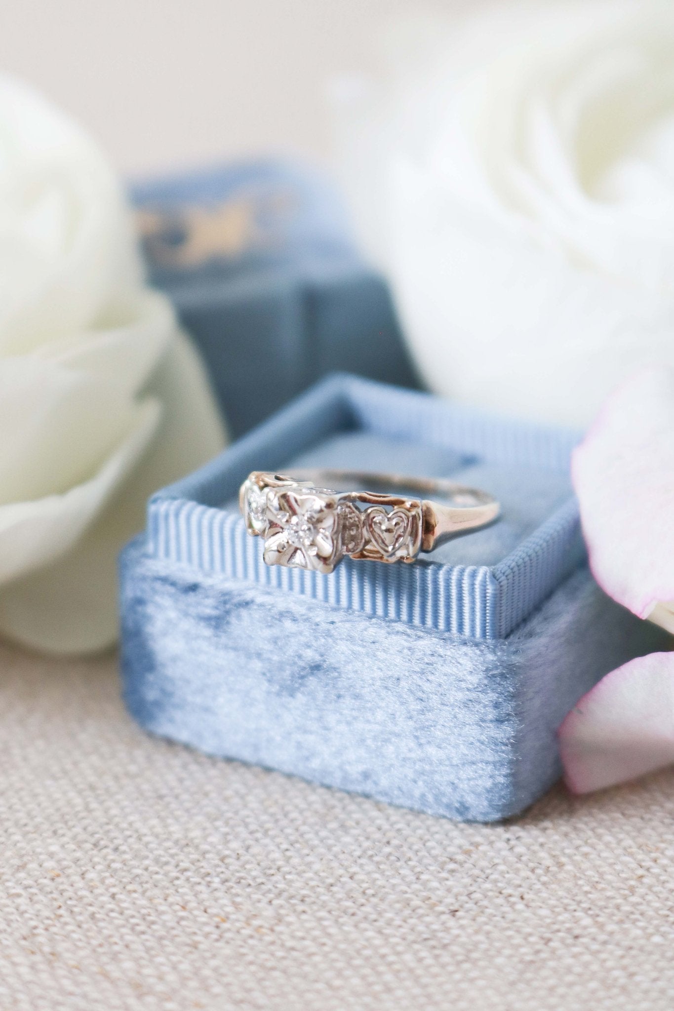 Front view of Yellow and White Gold Vintage Engagement Ring with Diamond Hearts on top of ring box. 