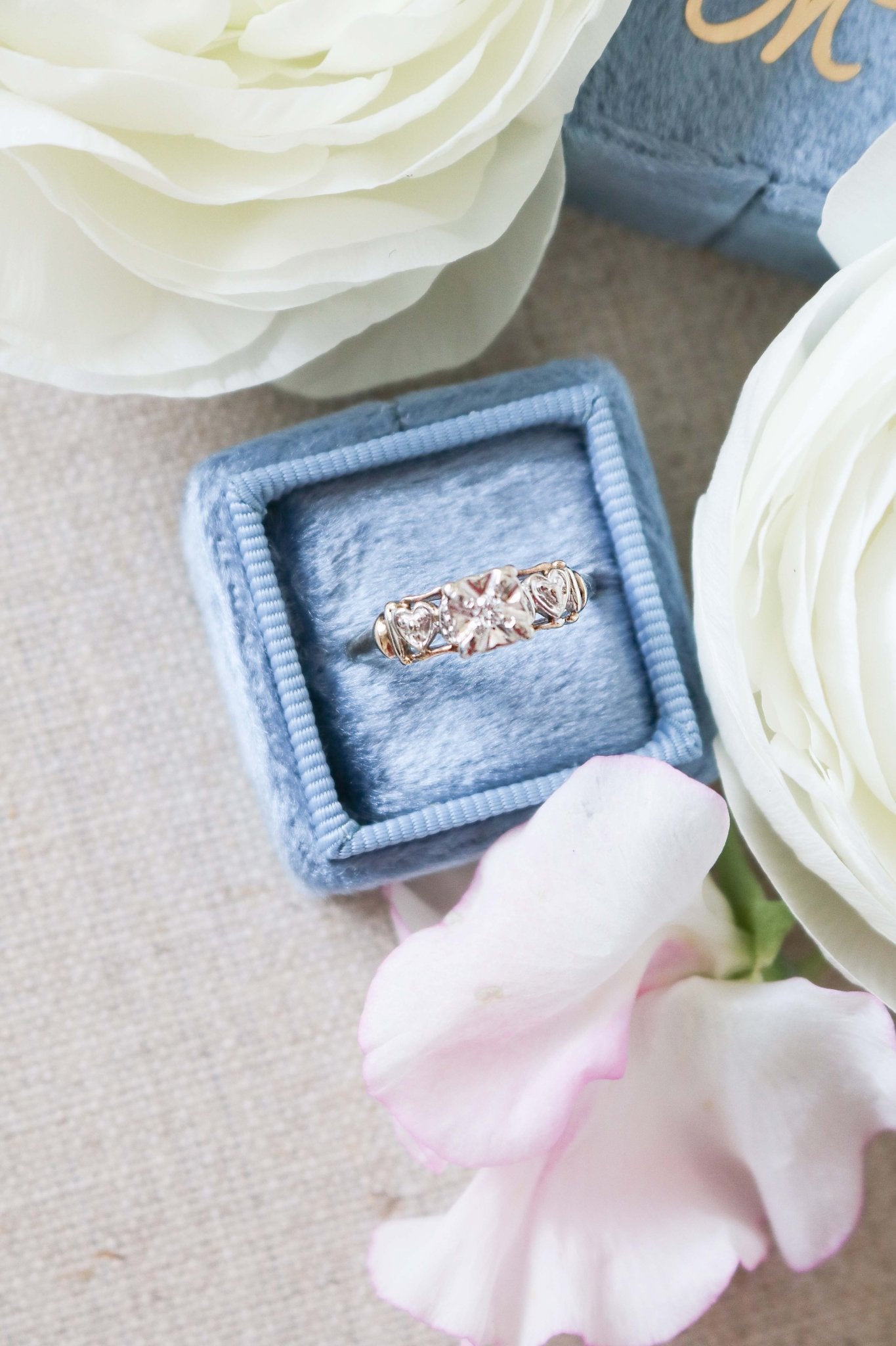 Top view of Yellow and White Gold Vintage Engagement Ring with Diamond Hearts on top of ring box. 