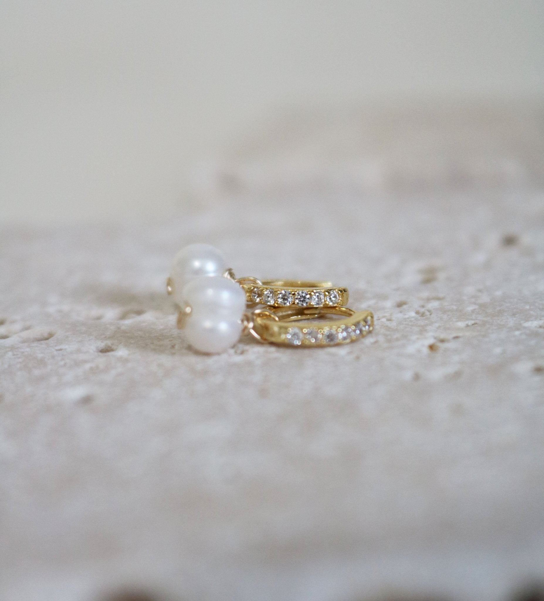 A pair of cubic zirconia encrusted gold-filled pearl huggies. 