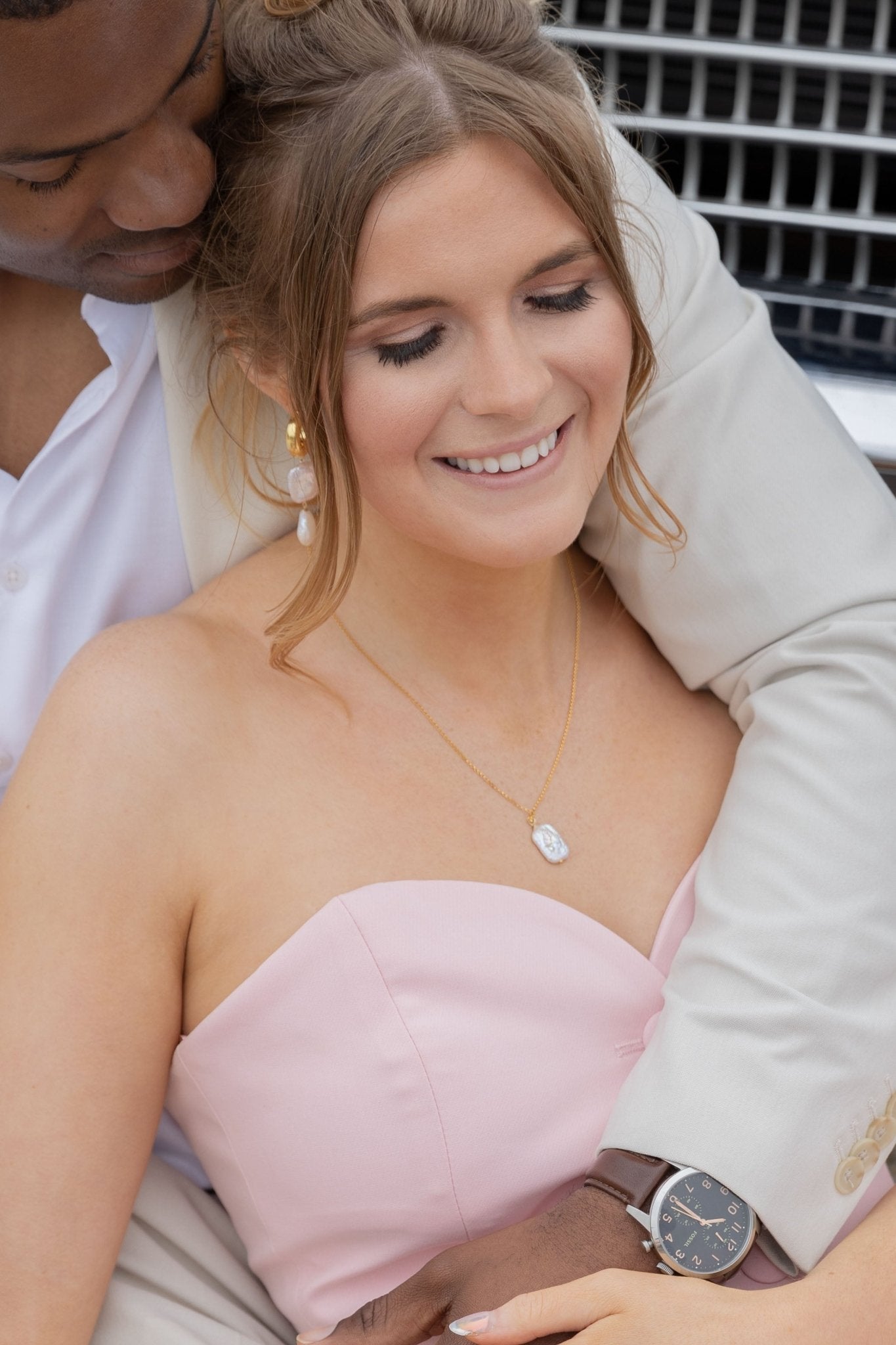 Groom holds his bride close as she showcases her pearl bridal jewelry. Handmade Canadian jewelry.