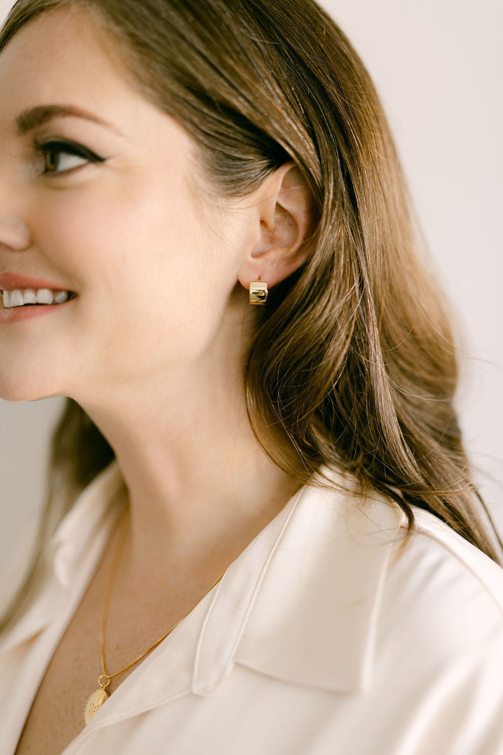 Woman wearing thick gold-filled huggie earrings. Modern jewelry Canada. Minimalist Jewelry. Everyday jewelry.