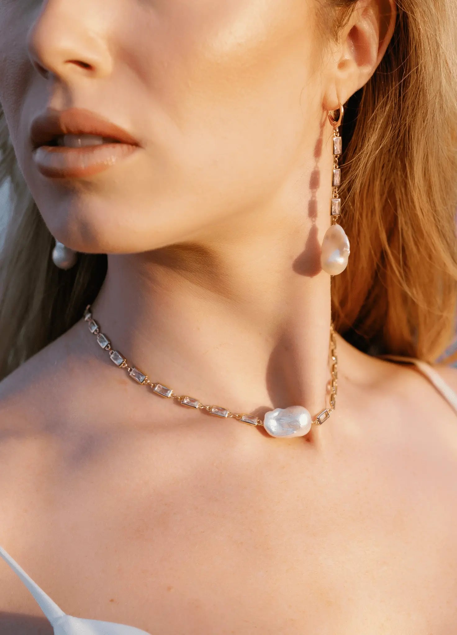 A close up of a bride wearing a stunning set of freshwater baroque pearl earrings and necklace with square cubic zirconia links. Handmade bridal jewelry, pearl jewelry sets, & Bridal jewelry Canada.