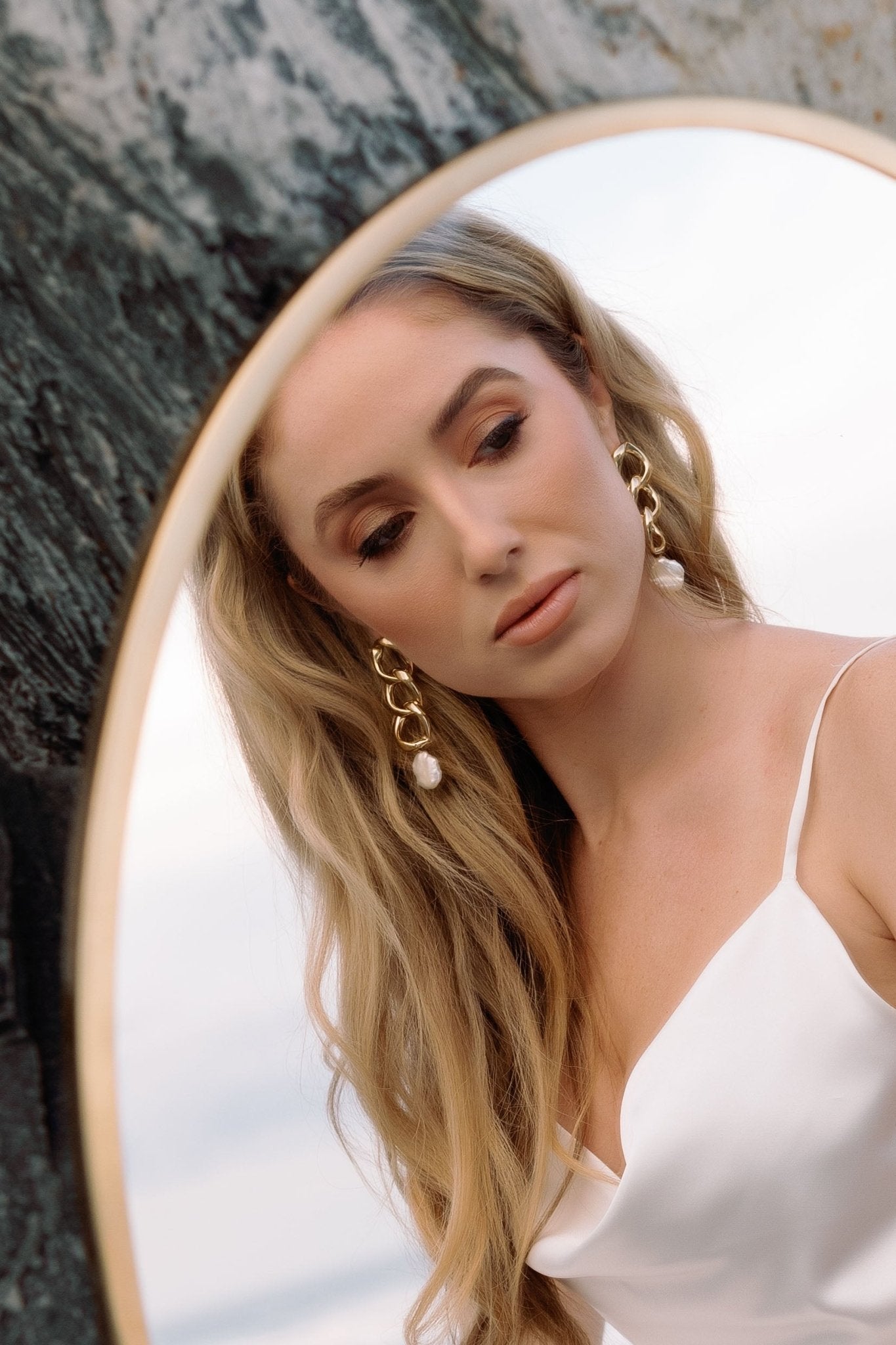 Mirror bride gazes at custom handmade wedding dress and puffy link gold-filled freshwater pearl earrings.