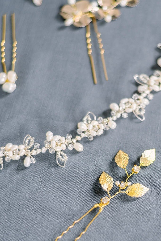 A close up of a gold crystal and freshwater pearl bridal hairvine surrounded by hairpins.