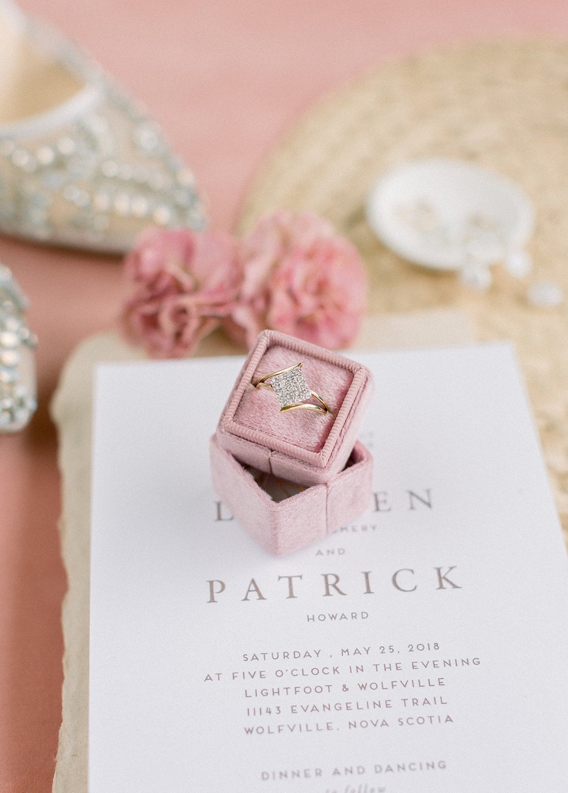 A Vintage Engagement Ring in 10k Yellow & White Gold with Diamonds sits in a pink square ring box on top of a wedding invitation. 