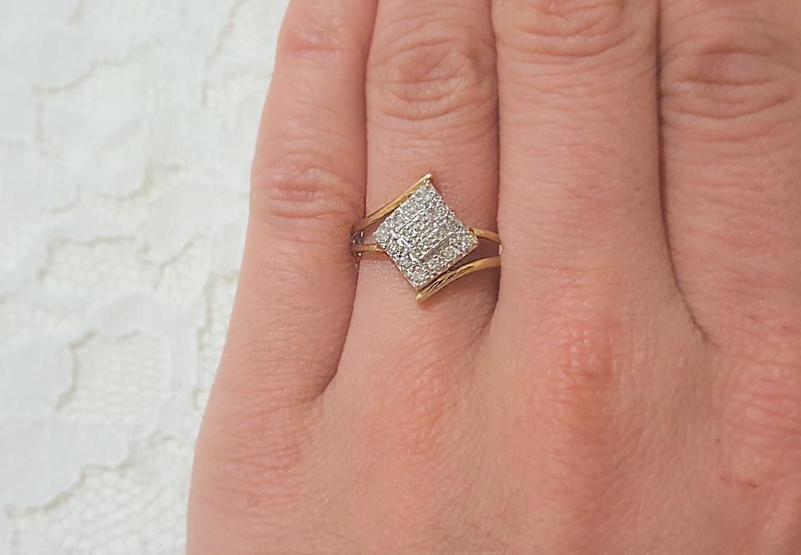 Close up of a 10k yellow/white gold diamond vintage engagement ring on a ring finger. 