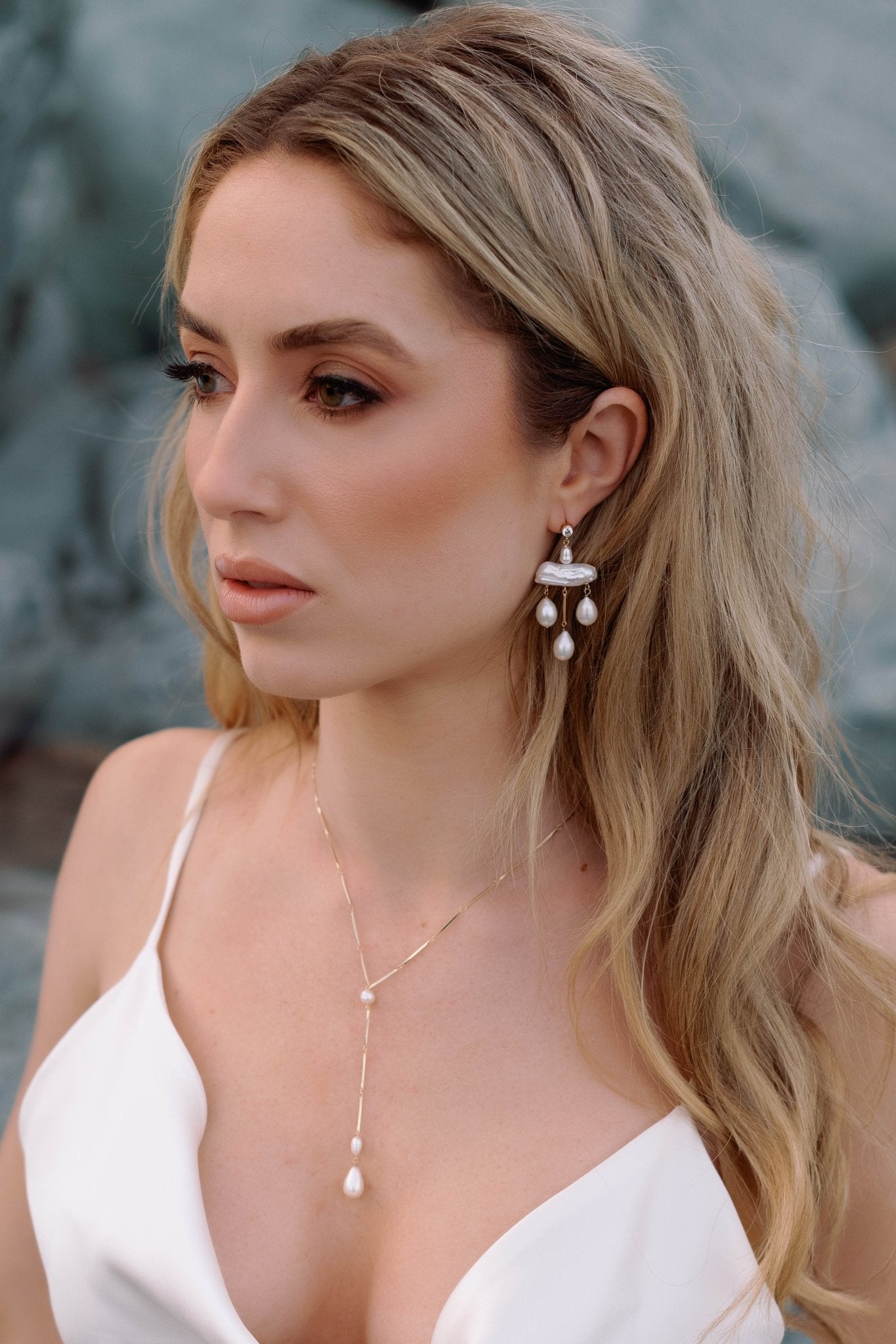 Bride on the beach with sleek wedding gown, a sterling silver drop necklace with pearls, and gold-filled statement chandelier earrings with freshwater pearls. 