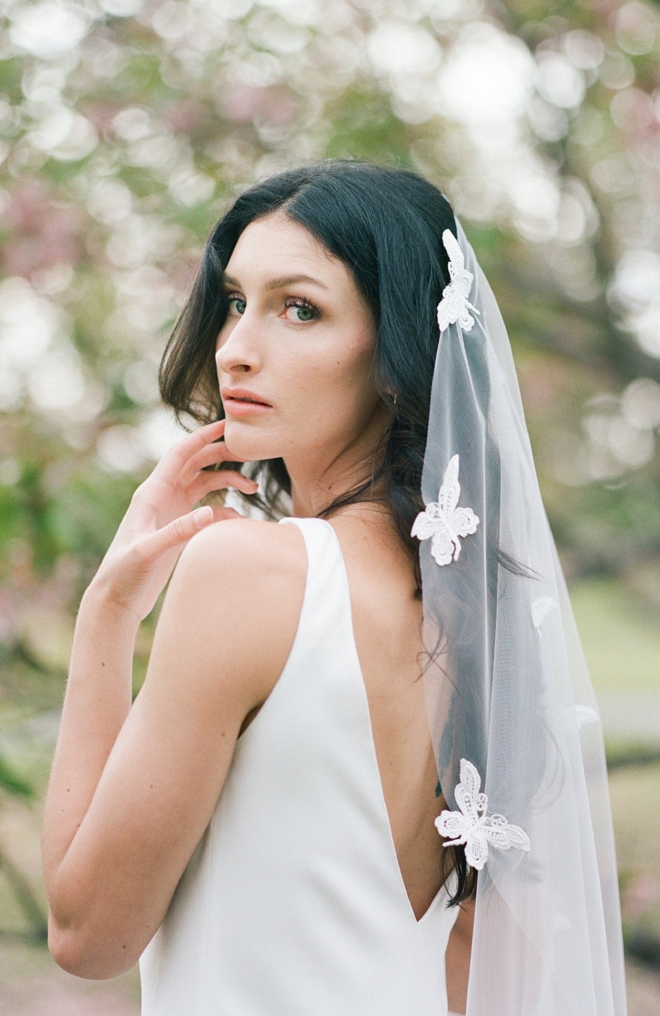 A bride looks over her shoulder; her butterfly lace wedding veil flowing behind her. Canadian weddings. Wedding Canada. Wedding veils Canada. Bridal Hair Accessories. Bridal Accessories. Canadian Bridal Accessories. Handmade Canadian Accessories. Canadian handmade Accessories. Canadian designer. Canadian artist.