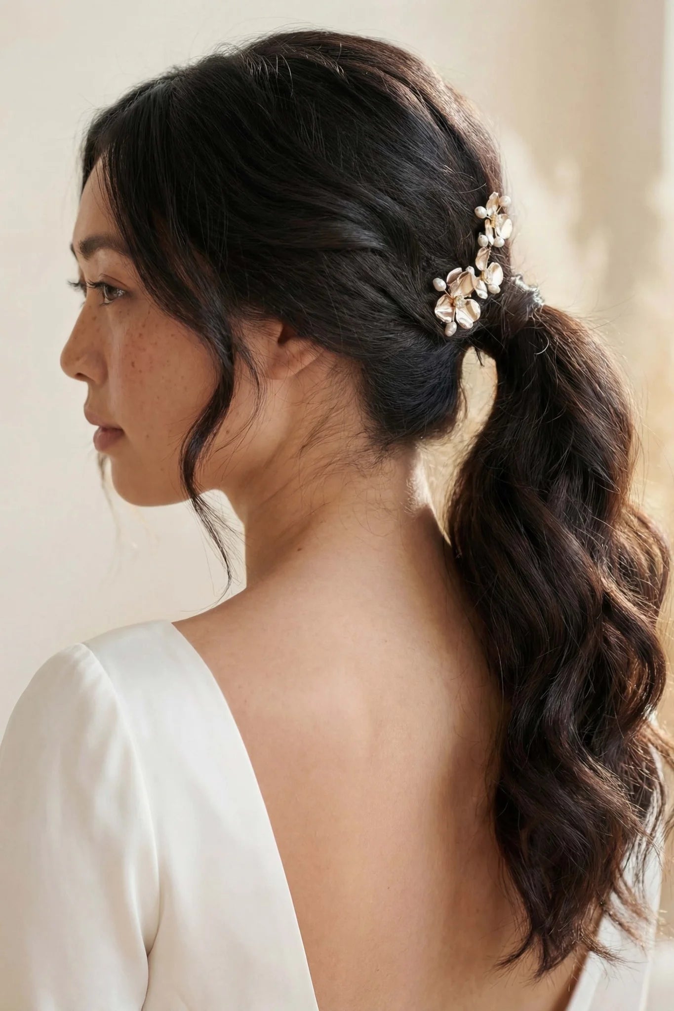 A gold flower bridal hairpin on a Filipina bride with freshwater pearls and crystals on a neutral background. Handmade bridal accessories and pearl bridal hair accessories by Canadian jewelry designer.