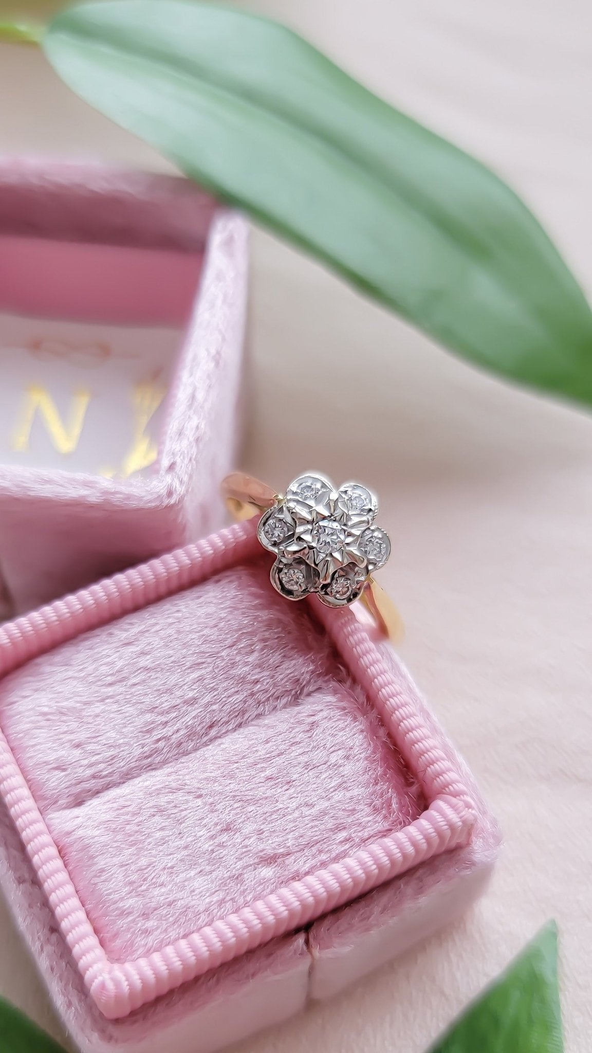 A close up top view of an 18ct Gold and Diamond Vintage Engagement Ring leaning against a pink ring box. 