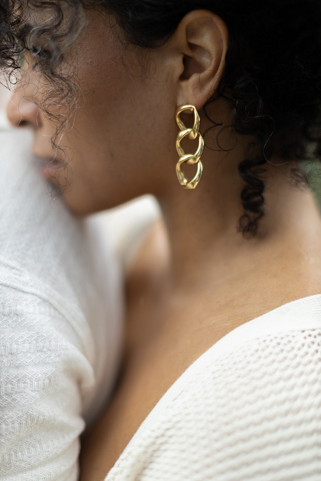 Woman rests her chin on a shoulder, showing off her Puffy Gold-Filled Chain Link Earrings. Gold-filled jewelry Canada. Handmade jewelry Canada. Handmade Canadian jewelry. Canadian handmade jewelry. Small Canadian jewelry brands. Canadian jewelry business. Statement Earrings.