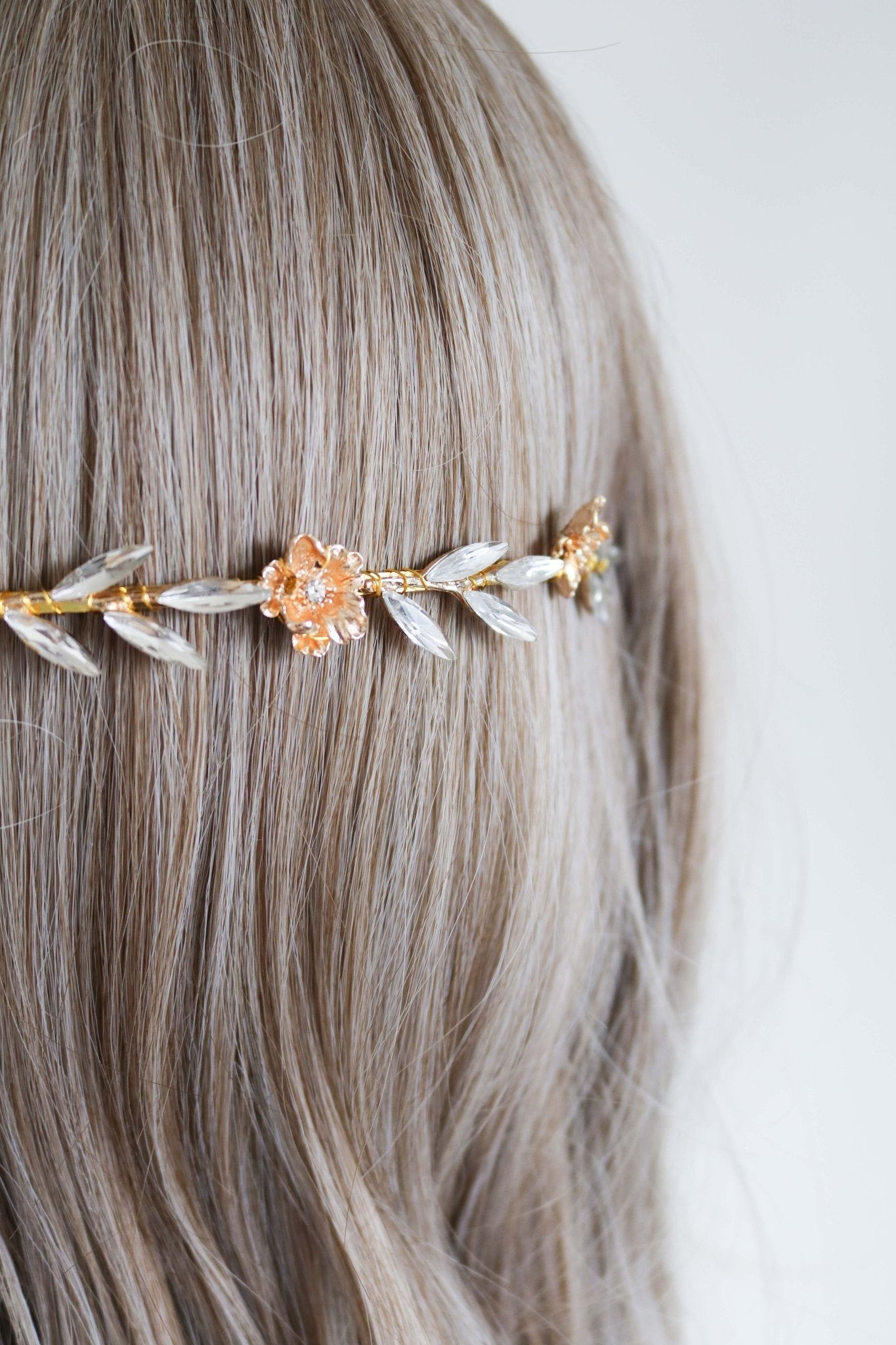 A close up of the Rosalie Crystal Leaf and Gold Rose Bridal Headband on a head bust with wig. 